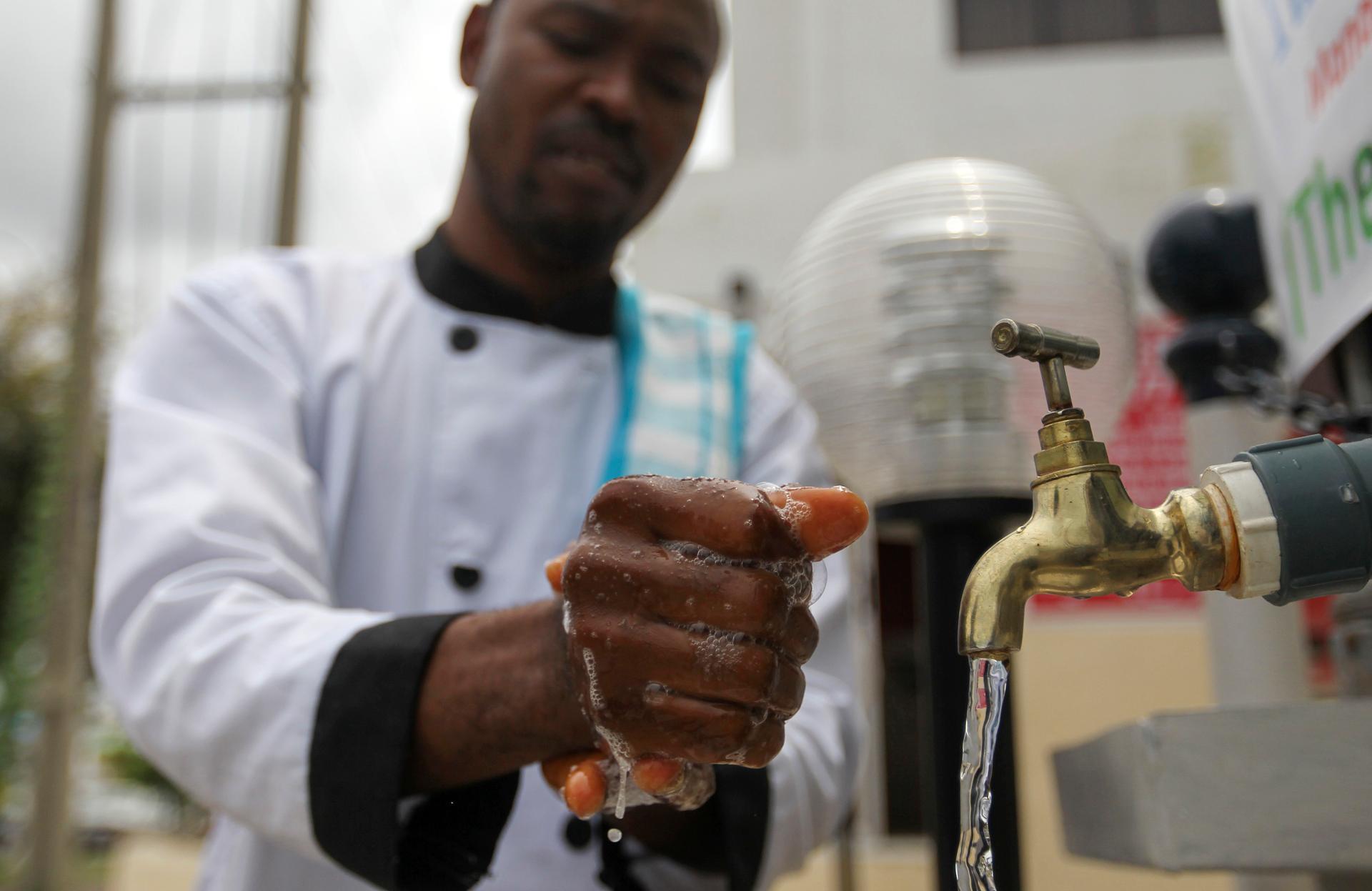 A man washes his hands at a facility outside the Green Pharmacy, Area 8, in Abuja, Nigeria on September 1, 2014.