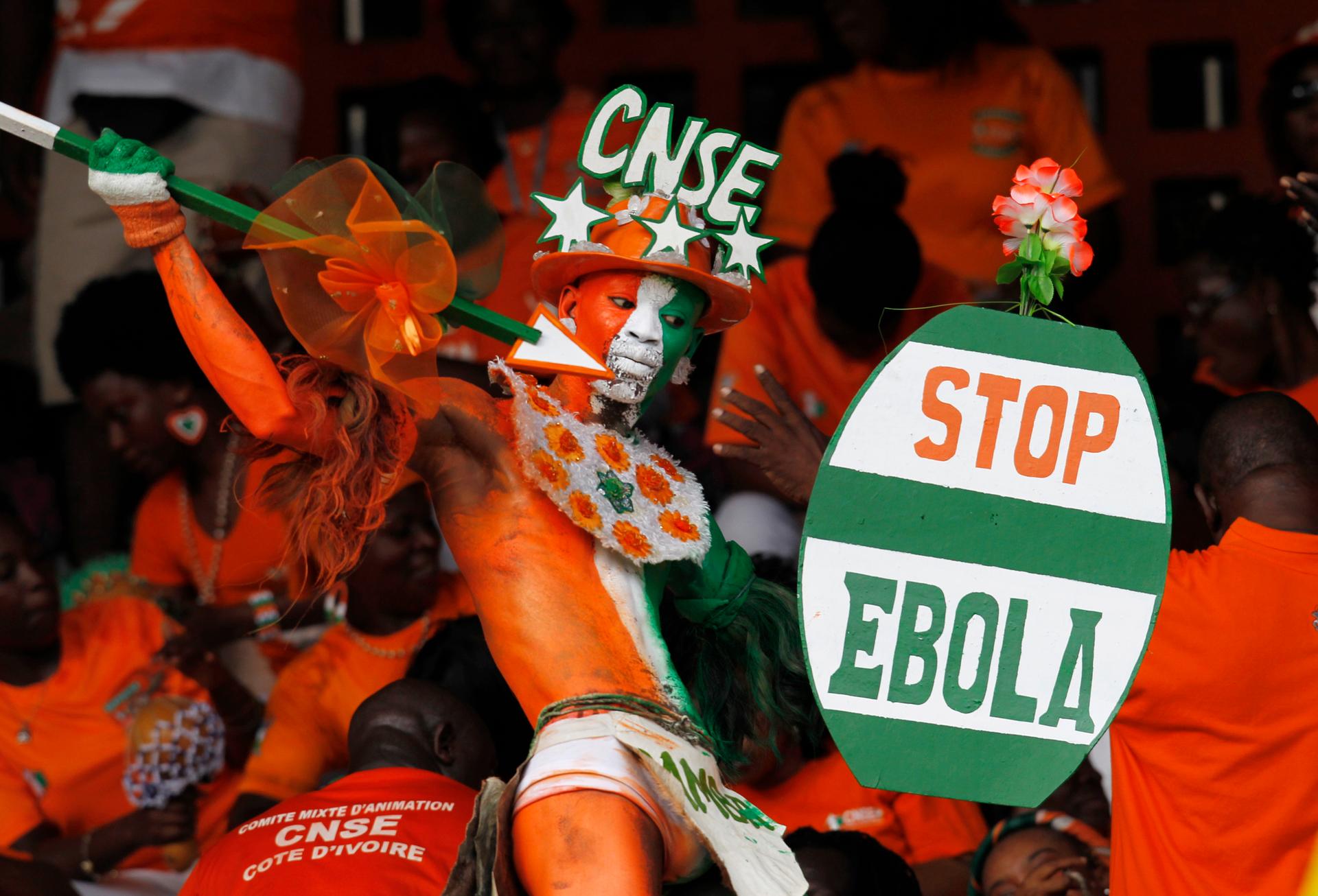 A fan of Ivory coast holds a sign with a message against Ebola during the 2015 African Nations Cup qualifying soccer match between Ivory Coast and Sierra Leone.