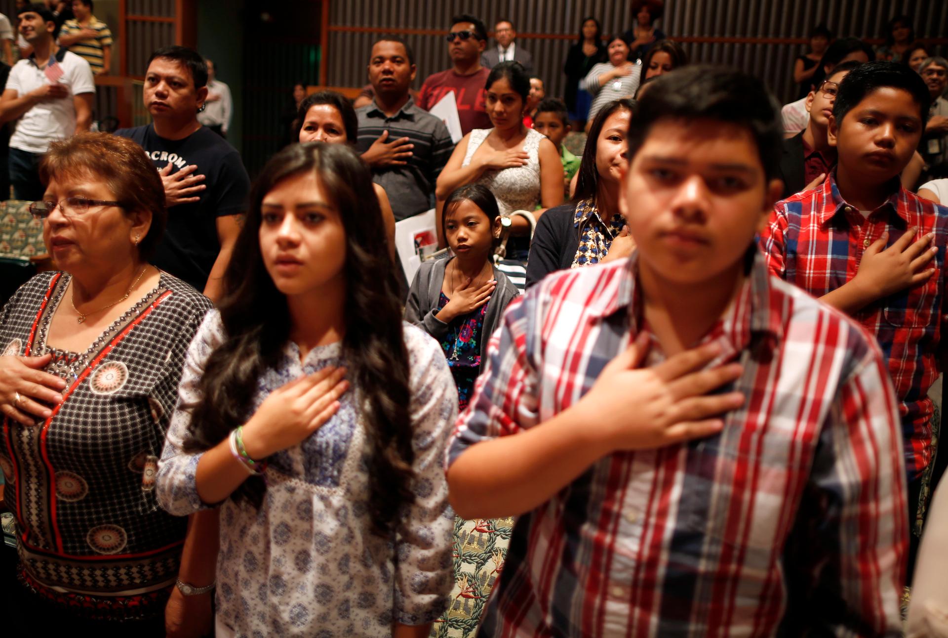 People say the pledge of allegiance at a US citizenship ceremony for 80 immigrant children and youths in Los Angeles.