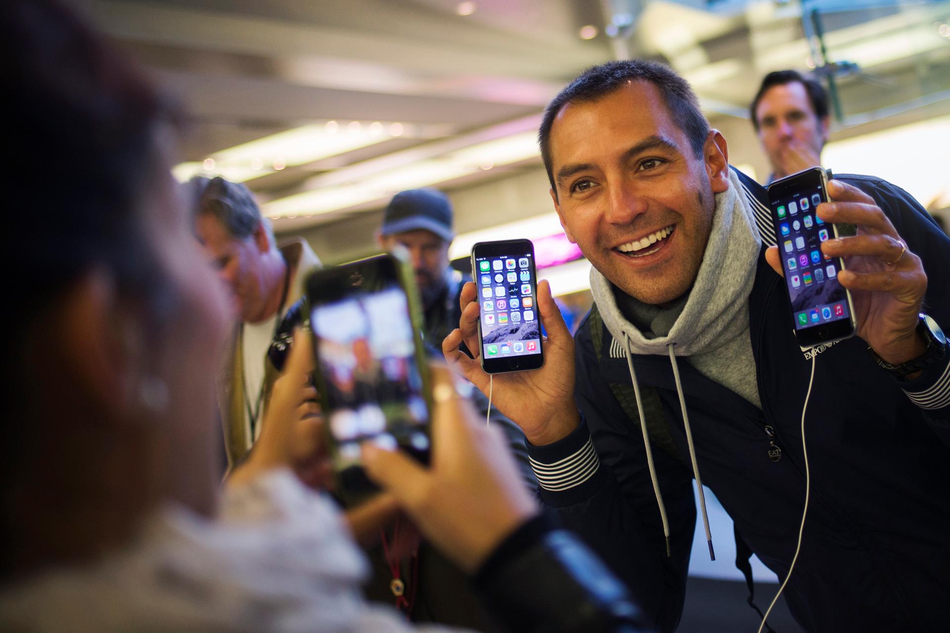 Michele Mattana of Sardinia, Italy, poses with an iPhone 6 Plus and an iPhone 6 on the first day of sales at the Fifth Avenue store in Manhattan on September 19, 2014.