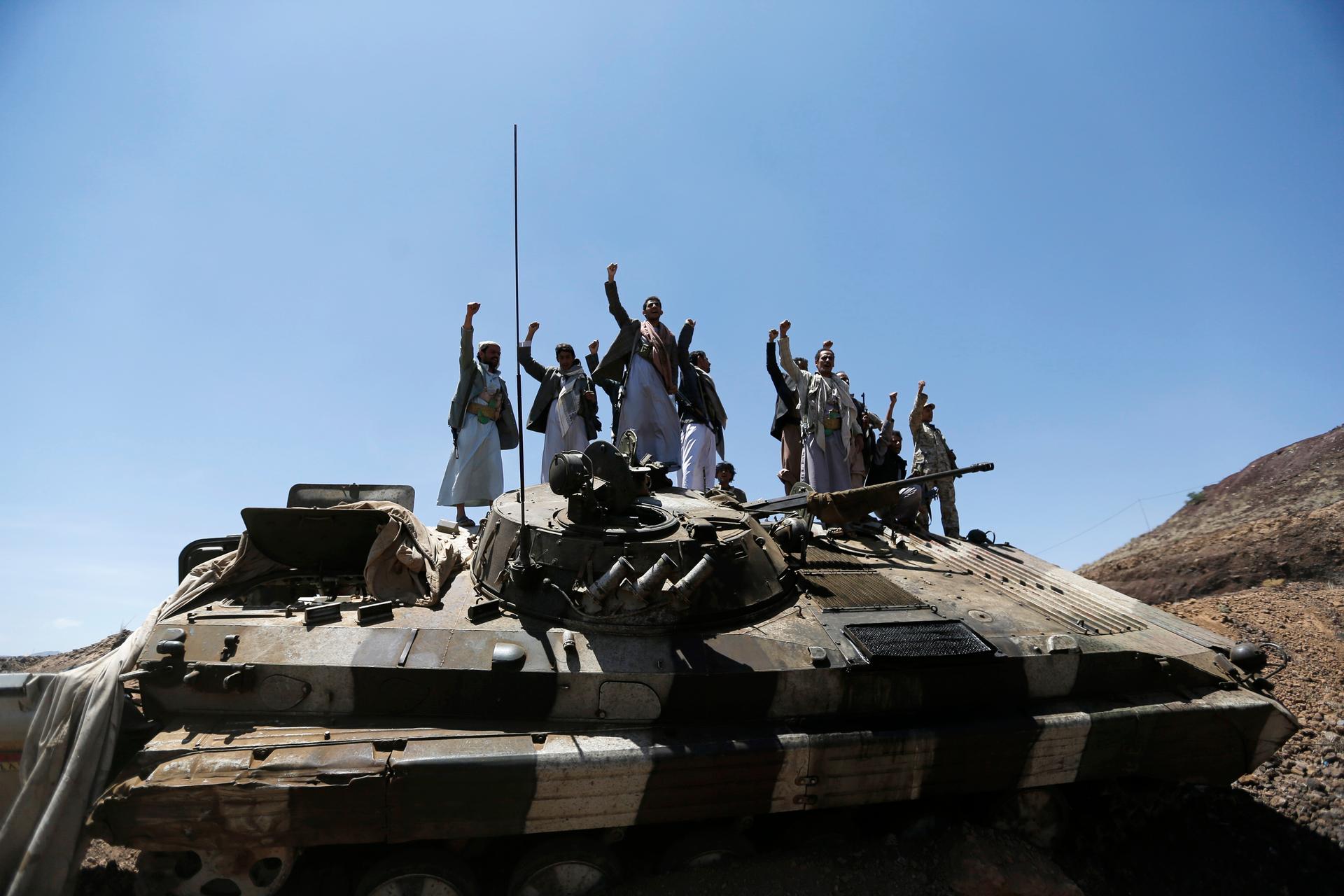 Shiite Houthi rebels gesture as they stand atop an army vehicle they took from the compound of the army's First Armoured Division in Sanaa on September 22, 2014.