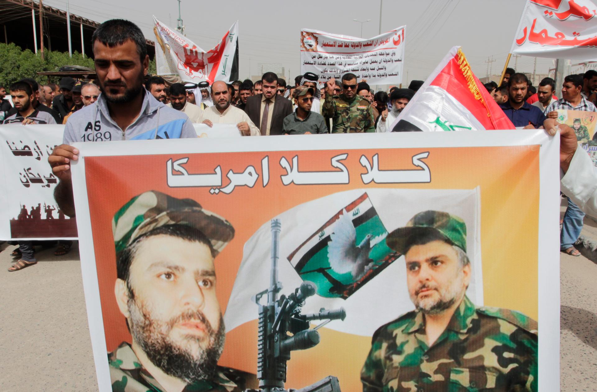 A demonstrator holds a banner with a picture of Shiite cleric Moqtada al-Sadr during a protest against the entry of American troops into Iraq on September 26, 2014. The words on the banner read "No No America."