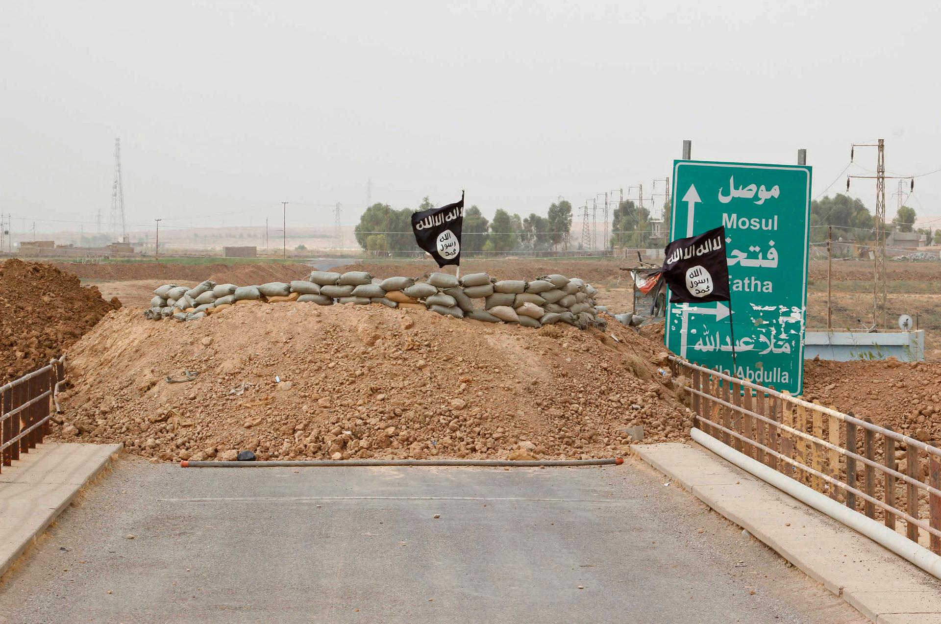 ISIS flags flutter on the Mullah Abdullah bridge in southern Kirkuk in early October 2014. The Iraqi Kurdish security forces are dug-in at the opposite end of the bridge. 