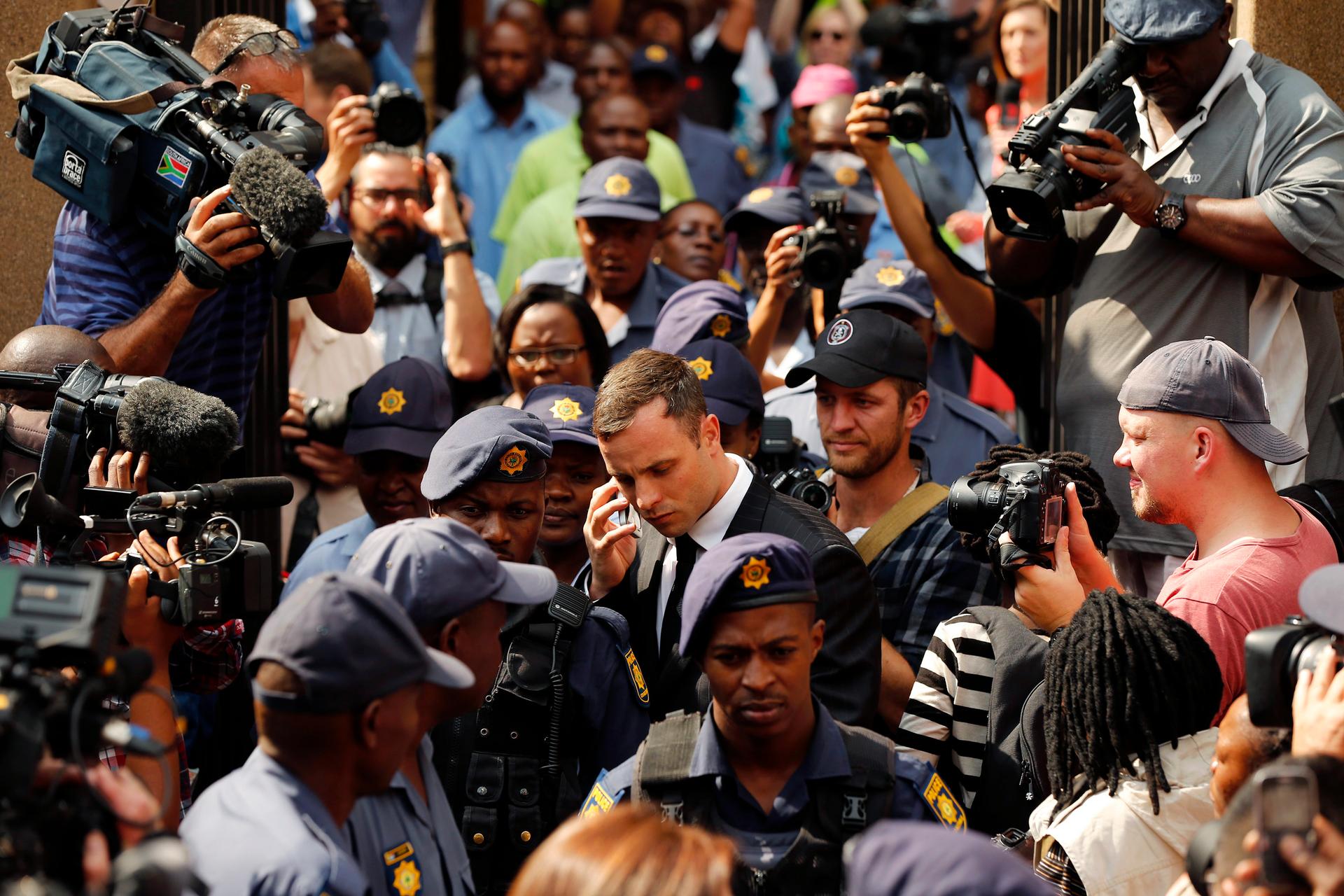 Olympic and Paralympic track star Oscar Pistorius uses his phone as he leaves the first day of his sentencing at North Gauteng High Court in Pretoria on October 13, 2014. 