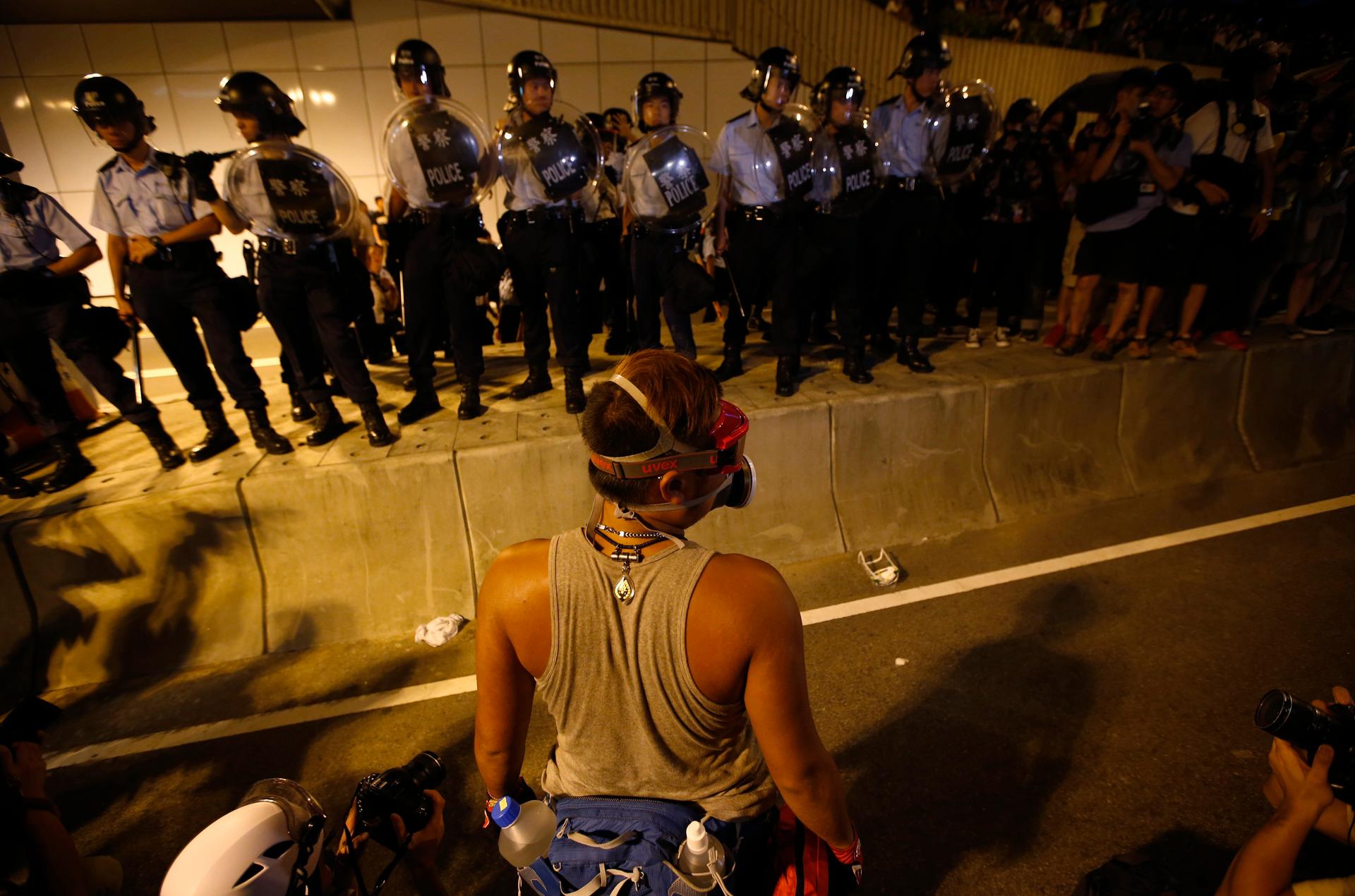A pro-democracy protester faces a police cordon as demonstrators continue to block an area outside of the government headquarters building in Hong Kong.