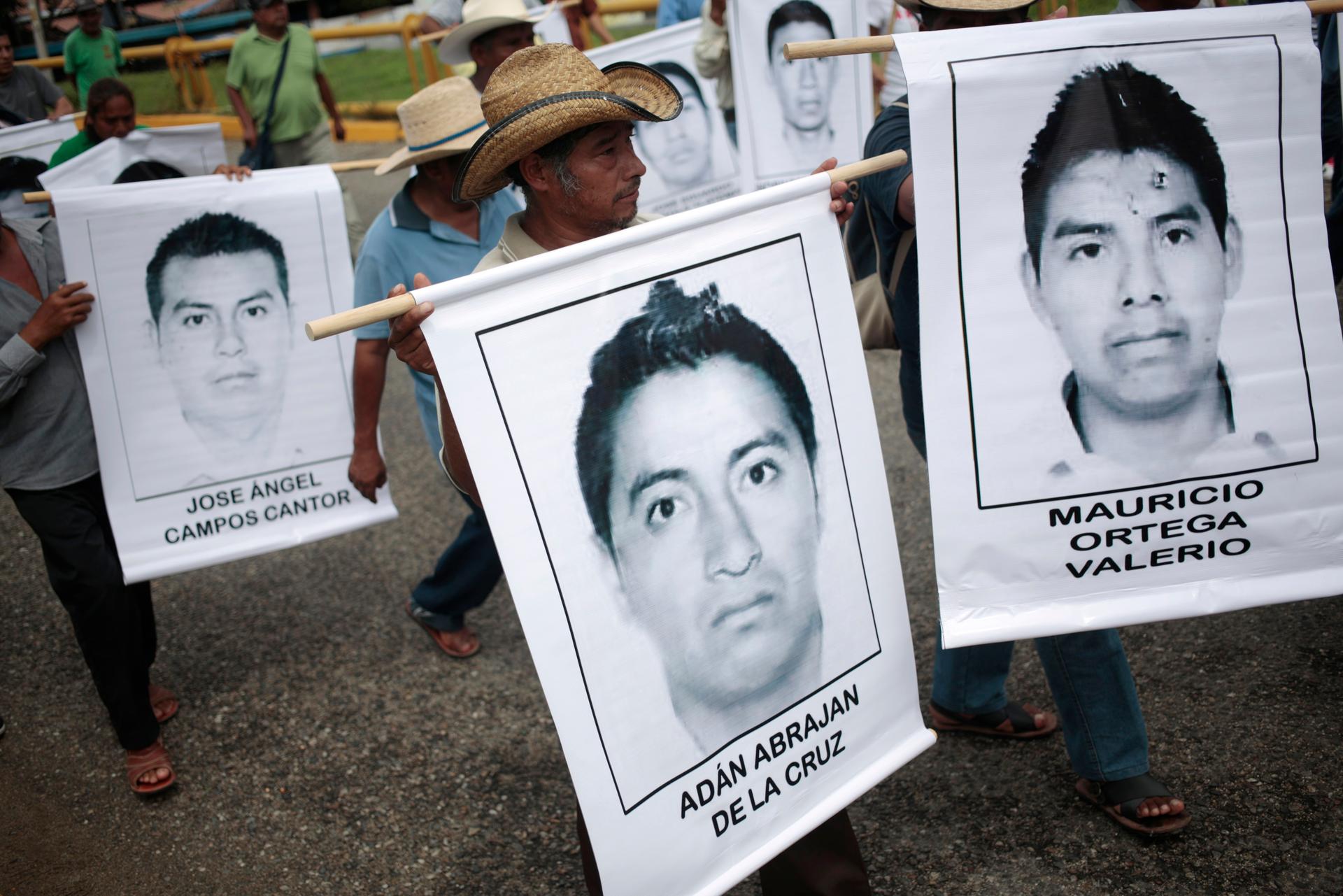People carry photographs of missing students during a march in Acapulco on October 17, 2014. On September 26, police allegedly linked to a criminal gang shot dead at least three students and abducted dozens of others during clashes in the southwestern cit