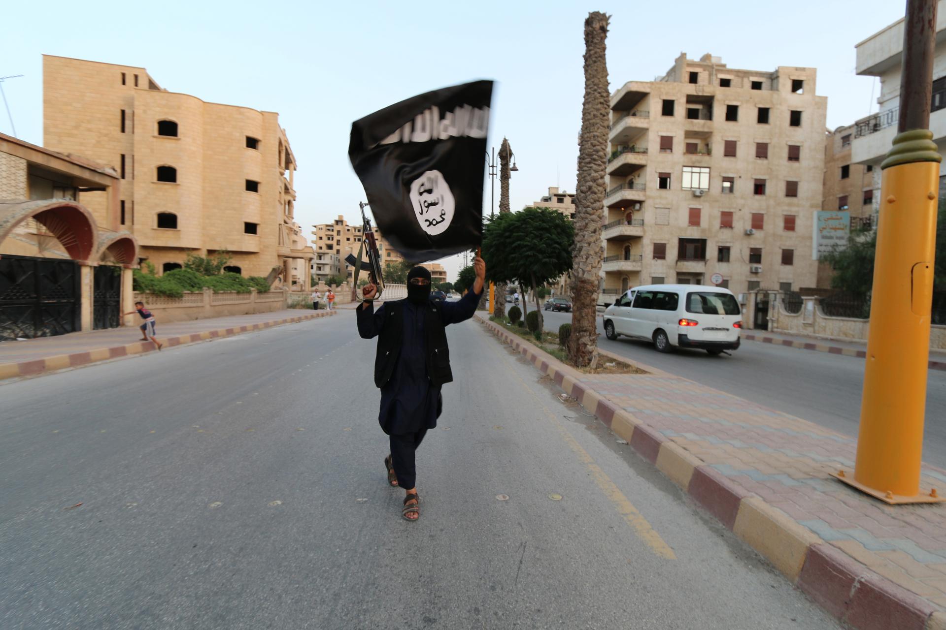 A member loyal to the ISIS waves the ISIS flag in Raqqa 
