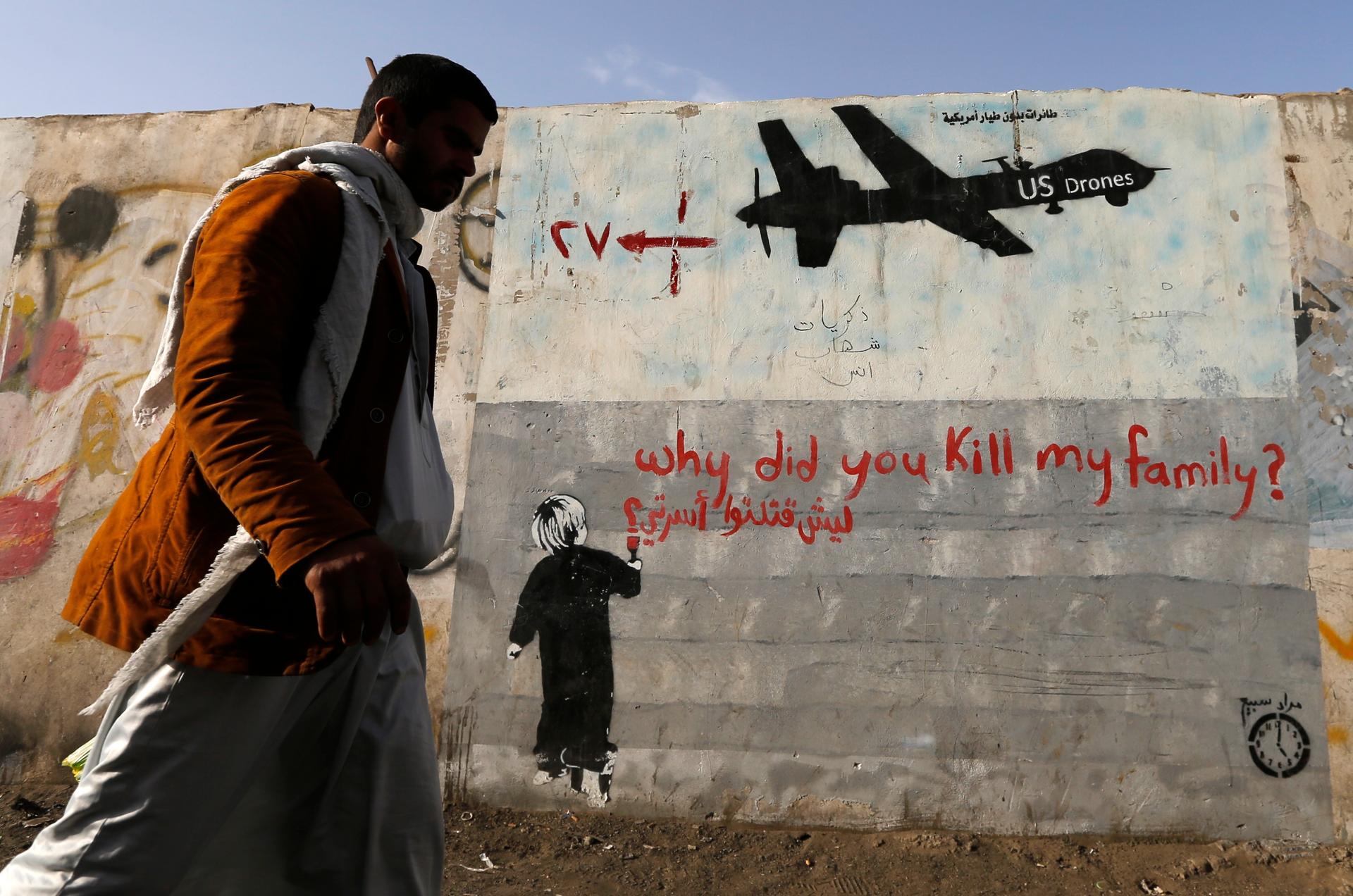 A man walks past graffiti denouncing US drone strikes in Yemen painted on a wall in Sana'a on November 13, 2014.