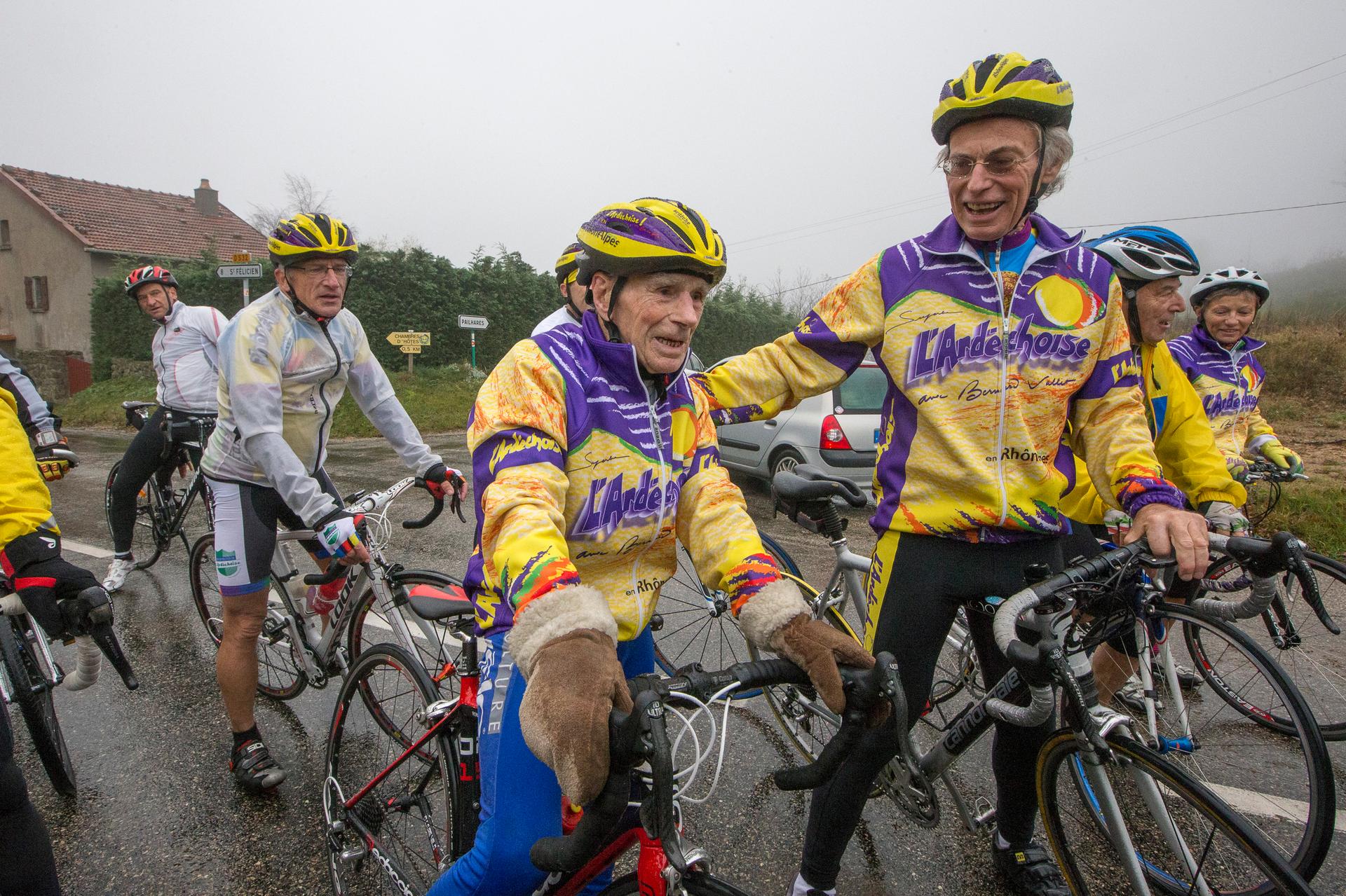 Robert Marchand (C), 103 years-old, speaks with riders as he makes his way along the Robert Marchand pass