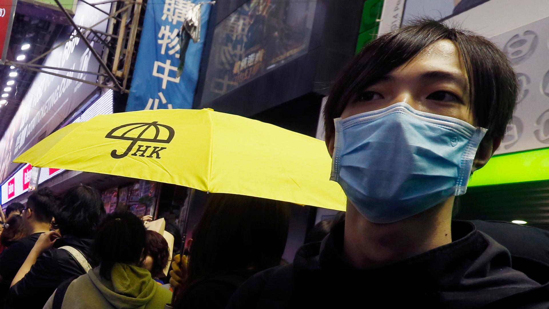 A pro-democracy protester carries a yellow umbrella, symbol of the Occupy Central civil disobedience movement, while gathering with other protesters at Mong Kok shopping district in Hong Kong on November 27, 2014. 