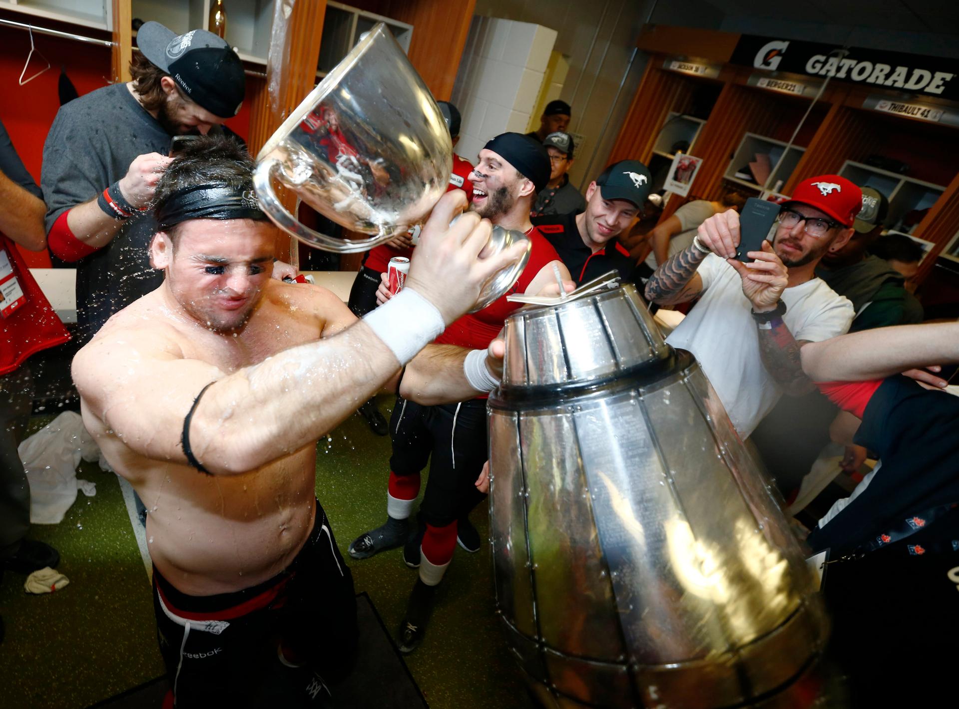 The Grey Cup splits into two pieces as Calgary Stampeders' Matt Walter celebrates in the locker room after his team defeated the Hamilton Tiger Cats in the CFL's 102nd Grey Cup football championship in Vancouver, BC, November 30, 2014.