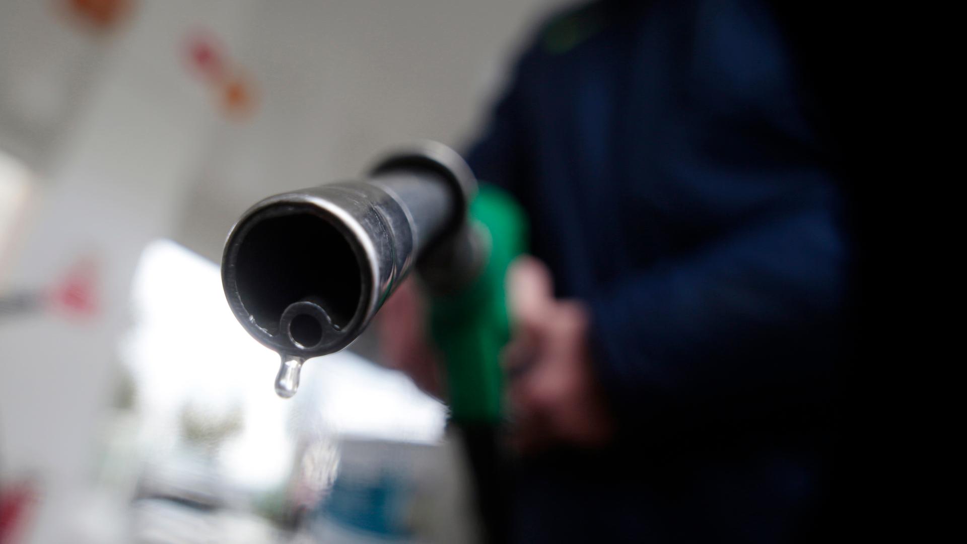 A customer holds a nozzle to fill up his tank in a gasoline station in Nice December 5, 2014. 