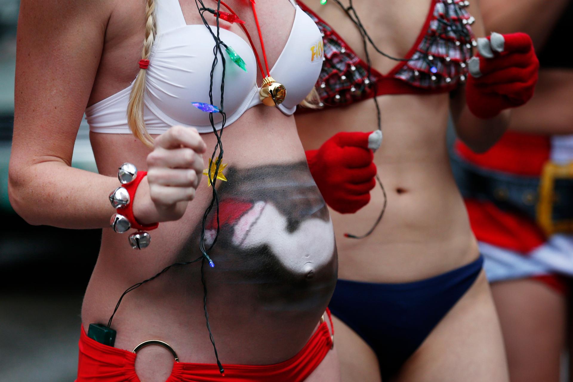 A pregnant woman with a painted stomach participates in the 15th annual Santa Speedo Run through the streets of the Back Bay in Boston.