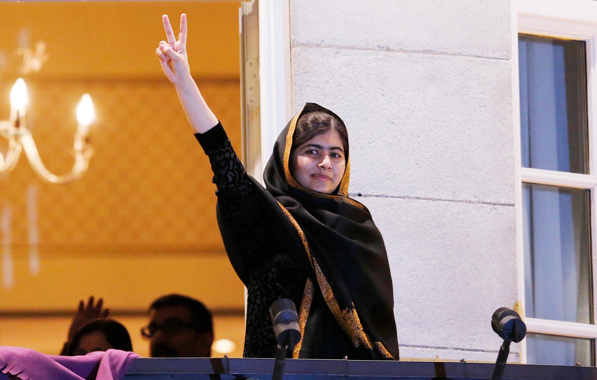 Nobel Peace Prize winner Malala Yousafzai flashes the peace sign from the balcony of the Grand Hotel in Oslo on December 10, 2014.