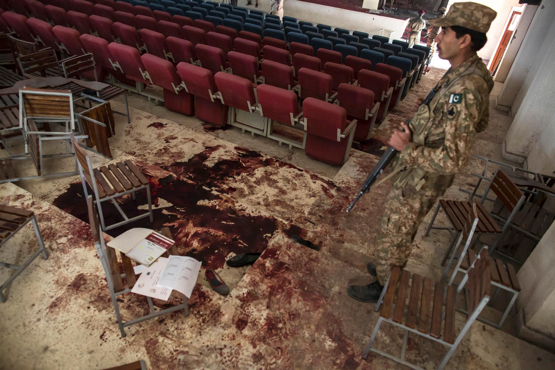 An army soldier stands by blood on the floor at the Army Public School, which was attacked by Taliban gunmen, in Peshawar on December 17, 2014.