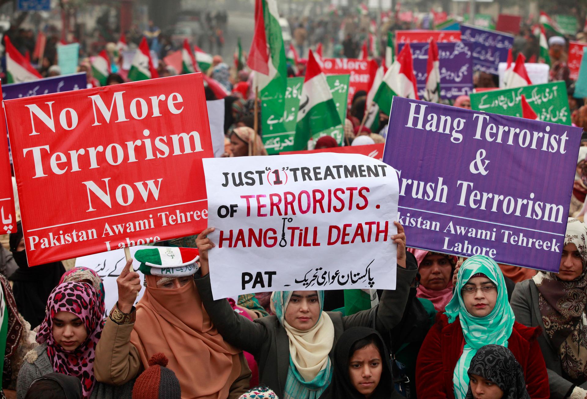 Supporters of Pakistani political party Pakistan Awami Tehreek hold signs to condemn the attack by Taliban gunmen on the Army Public School in Peshawar during a rally in Lahore on December 21, 2014.