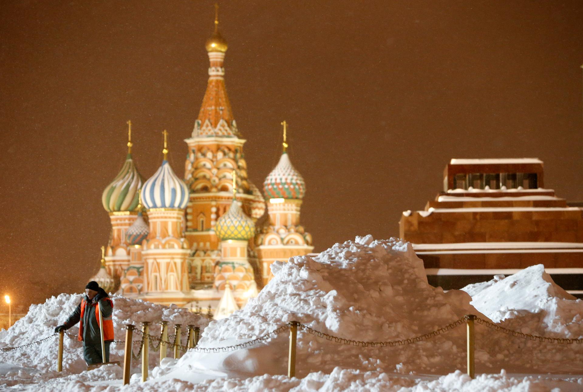 A worker removes snow in Red Square with St. Basil's Cathedral and the mausoleum of Soviet state founder Vladimir Lenin in the background.