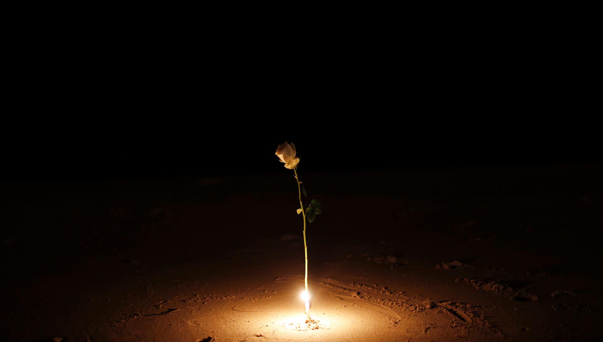 A rose is lit by a candle as survivors, local residents and visitors gather for a ceremony for victims of the 2004 tsunami in Ban Nam Khem, a fishing village destroyed by the wave. Survivors of Asia's 2004 tsunami and relatives of its 226,000 victims crie