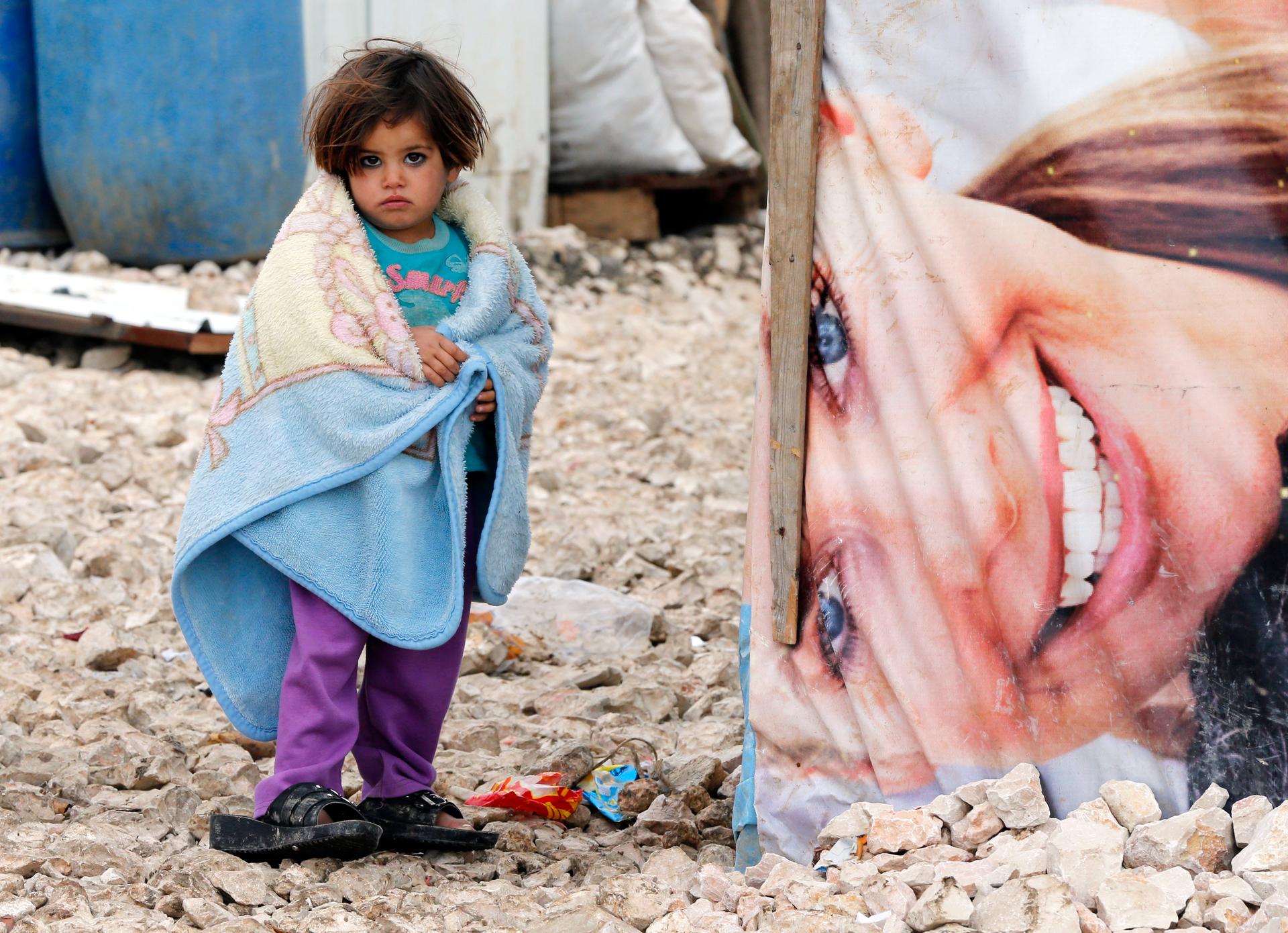A Syrian girl covers herself with a blanket at a refugee settlement in Bar Elias in Lebanon.