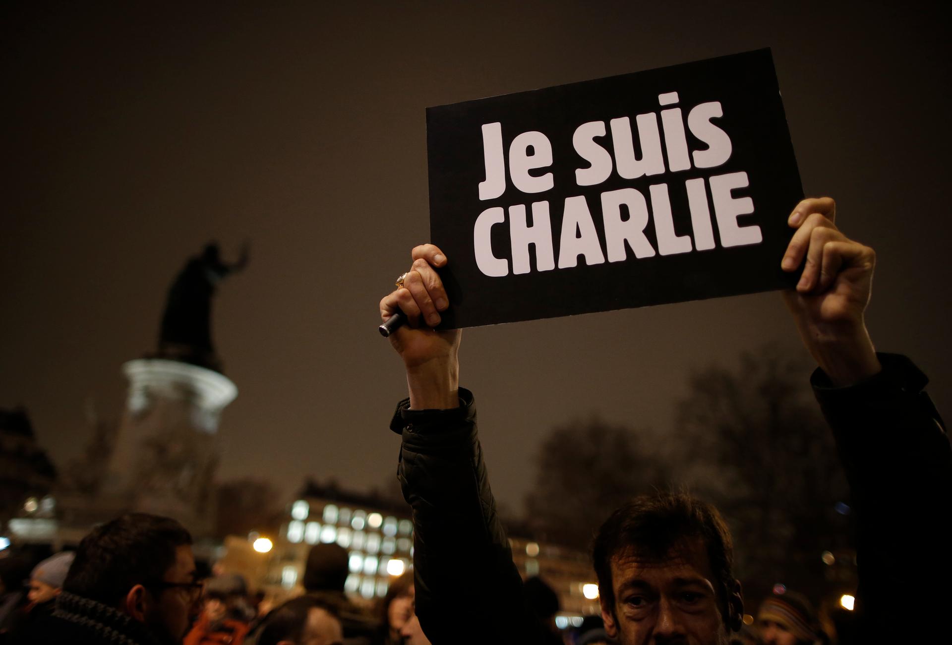 A man holds a placard which reads "I am Charlie" to pay tribute during a gathering at the Place de la Republique in Paris on the night of January 7, 2015, following a shooting by gunmen at the offices of the magazine.