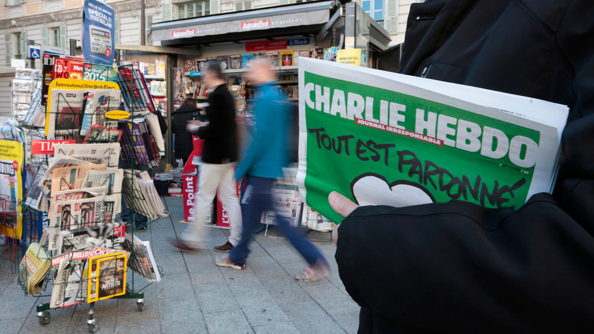 A man holds the new issue of satirical French weekly Charlie Hebdo, entitled "Tout est pardonné" ("All is forgiven"), at a kiosk in Nice on January 14, 2015.  