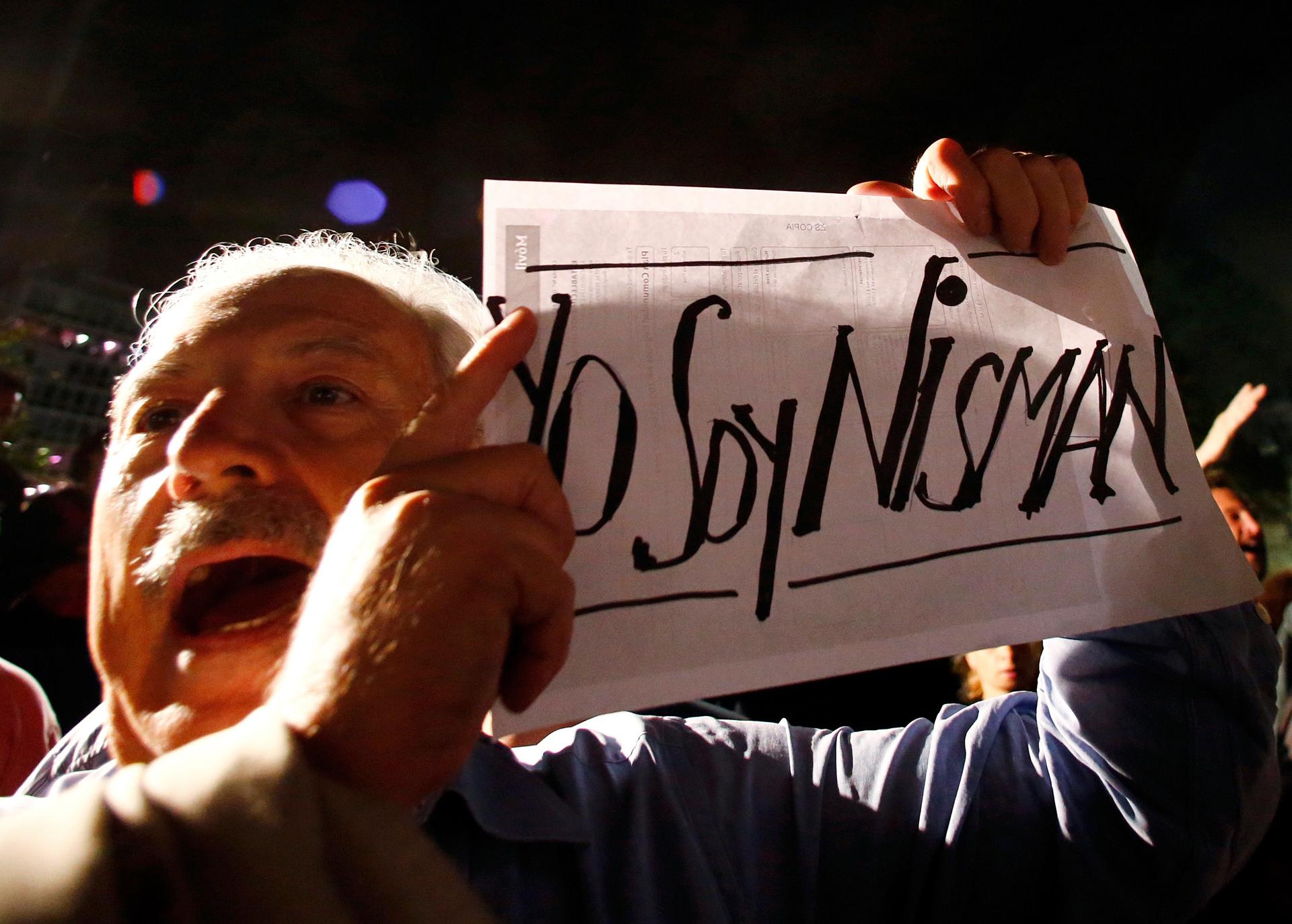 A demonstrator shouts slogans as he holds up a sign that reads 
