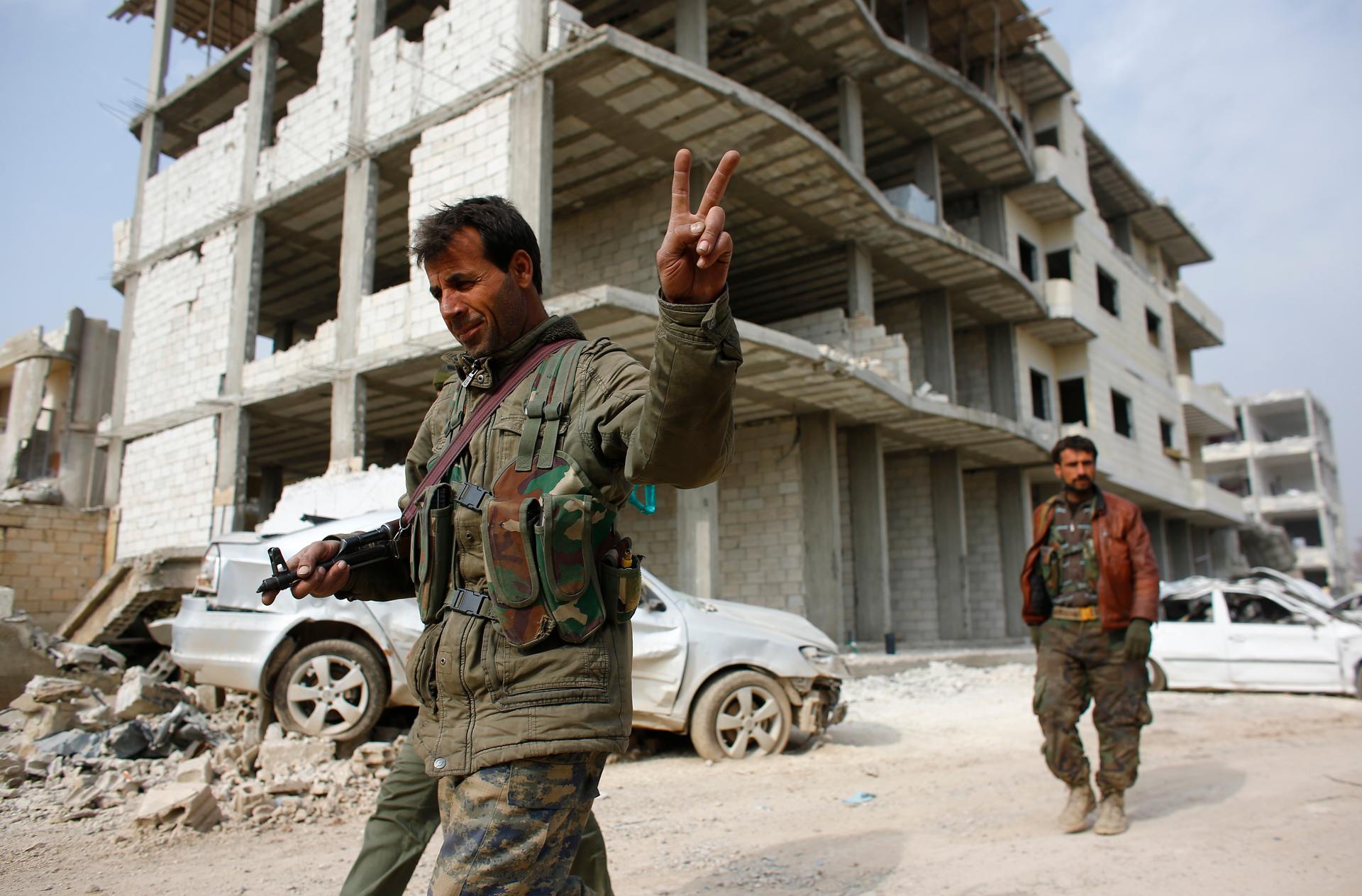 A fighter from the Kurdish People's Protection Units, or YPG, flashes a victory sign as he patrols the streets in the northern Syrian town of Kobane on January 28, 2015.