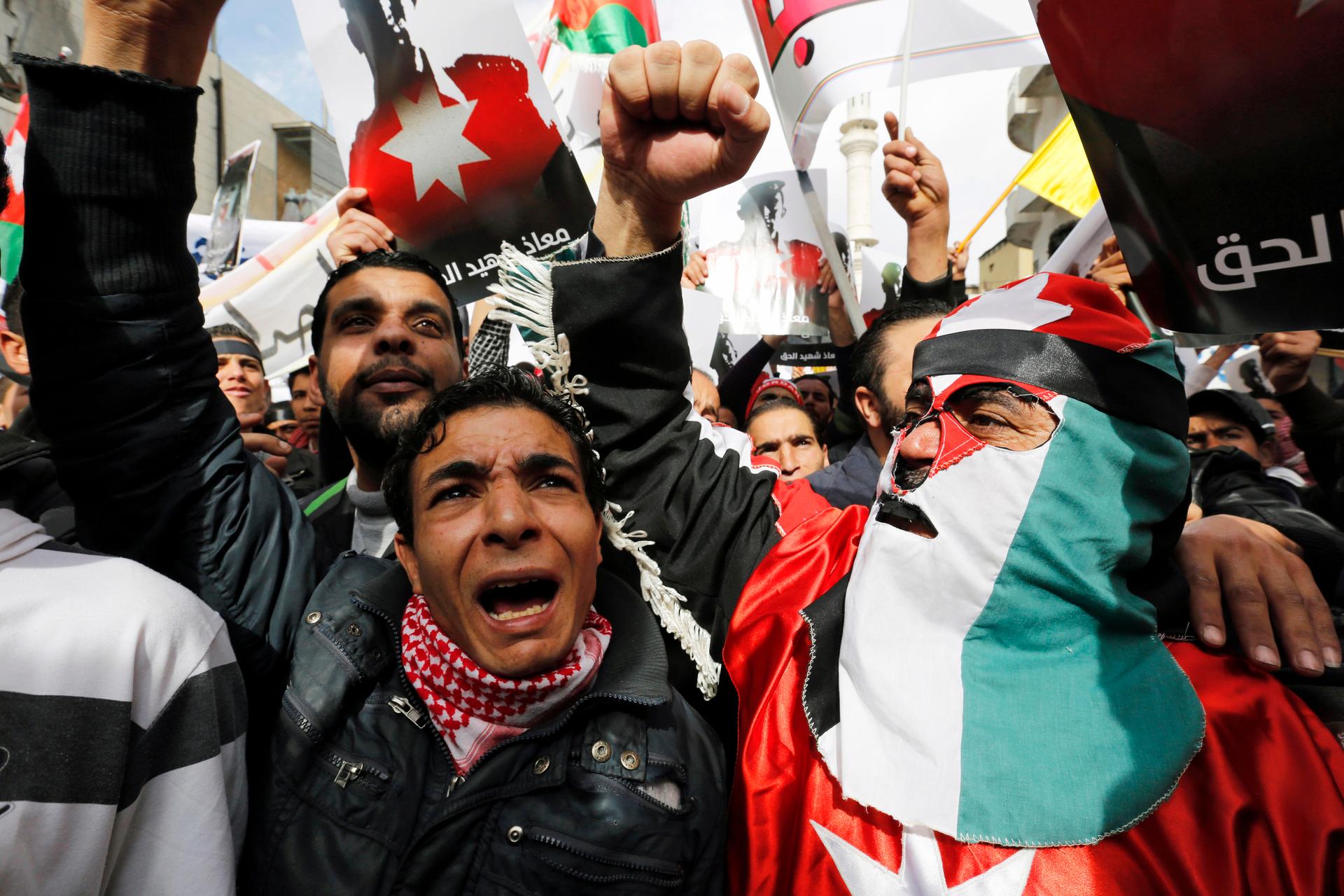 A protester dressed in a Jordanian flag joins others as they hold up pictures of Jordanian King Abdullah and Jordanian pilot Muath al-Kasaesbeh, while chanting slogans during a march after Friday prayers in downtown Amman February 6, 2015.