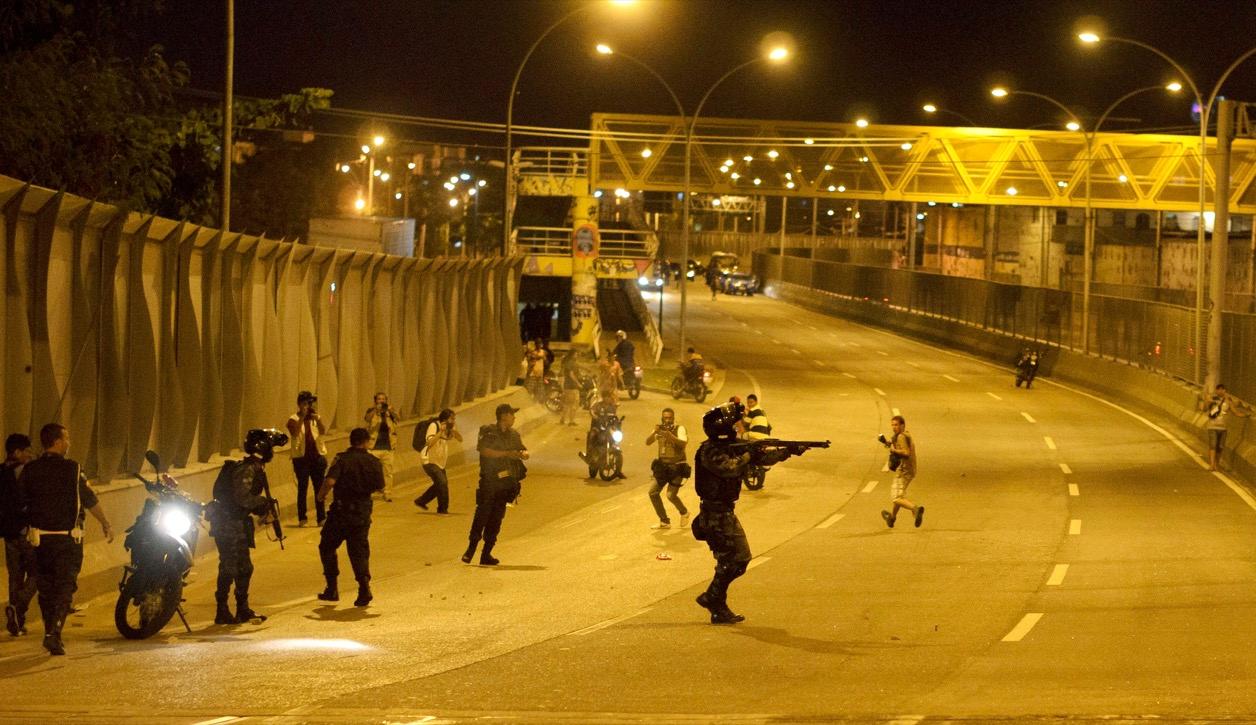 Policemen take positions during a shooting with suspected drug gangs on Linha Amarela highway near the Maré favela complex in Rio de Janeiro on Feb. 23, 2015.