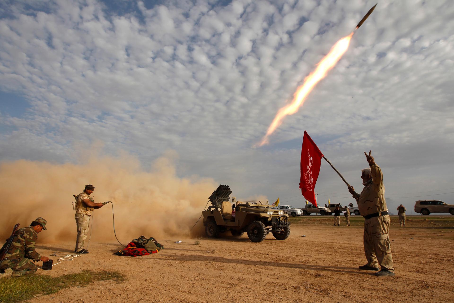 Shi'ite fighters launch a rocket during clashes with Islamic State militants on the outskirts of al-Alam March 8, 2015.