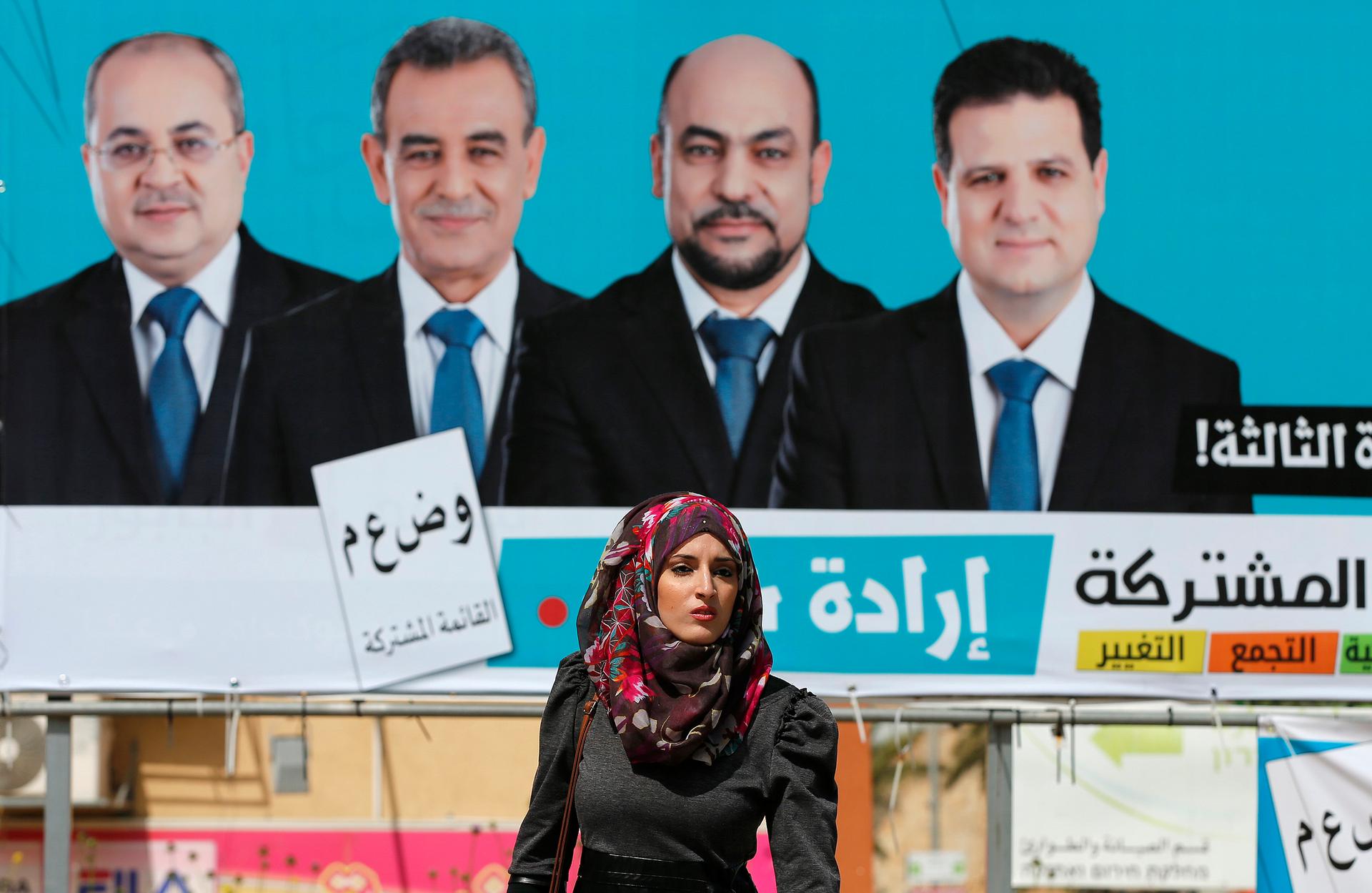 A woman walks past a Joint Arab List campaign billboard. Four Arab-Israeli political parties have united for the first time, making the group the third-largest political faction in the Knesset. 