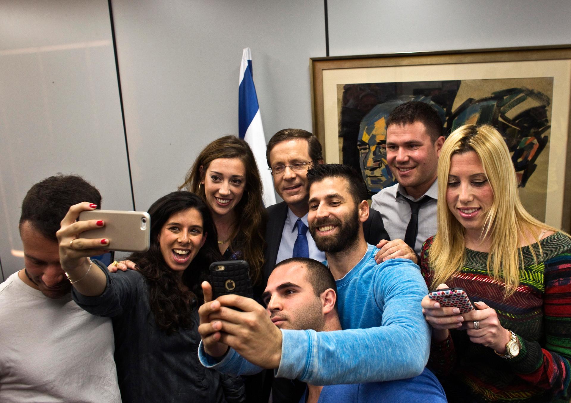 Isaac Herzog, at rear in the center, poses for a selfie with supporters of his center-left Zionist Union at their party headquarters in Tel Aviv on March 16, 2015. 