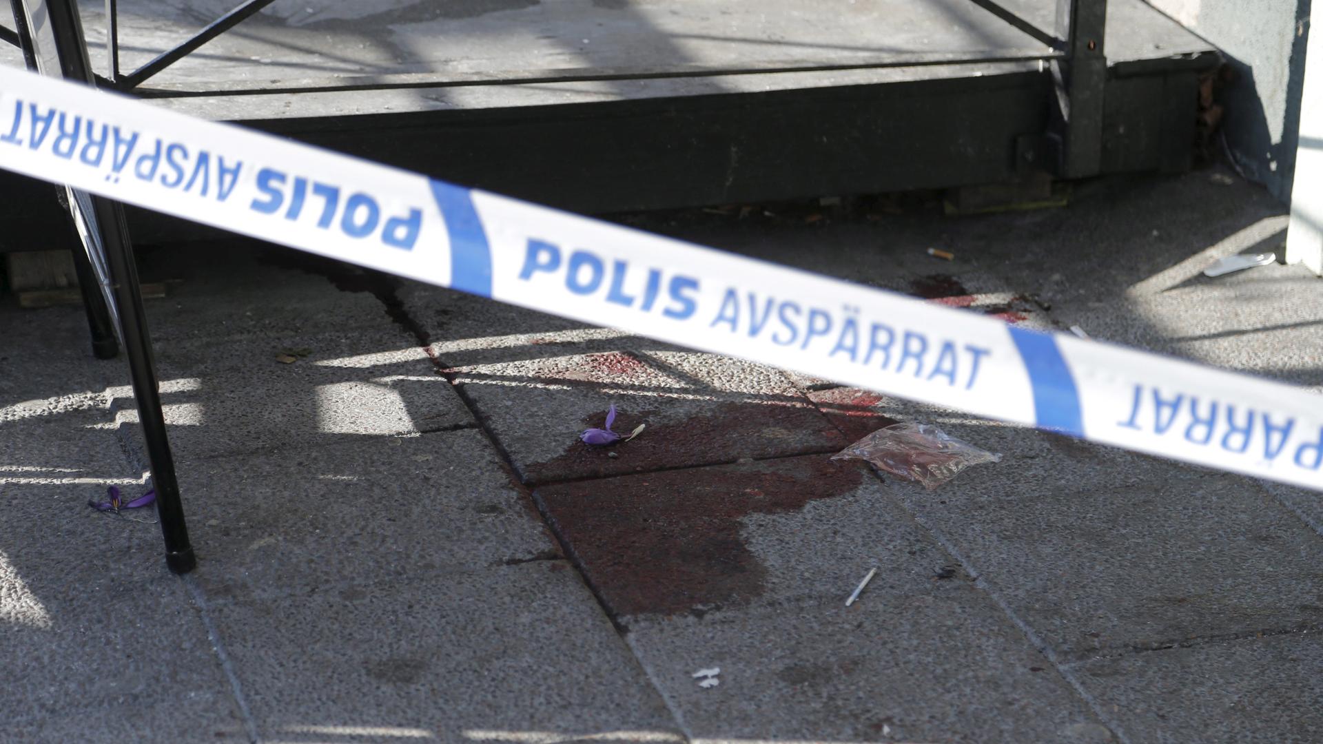 A bloodstain is seen behind police barrier tape at the scene of a fatal shooting in Gothenburg, March 18, 2015. 