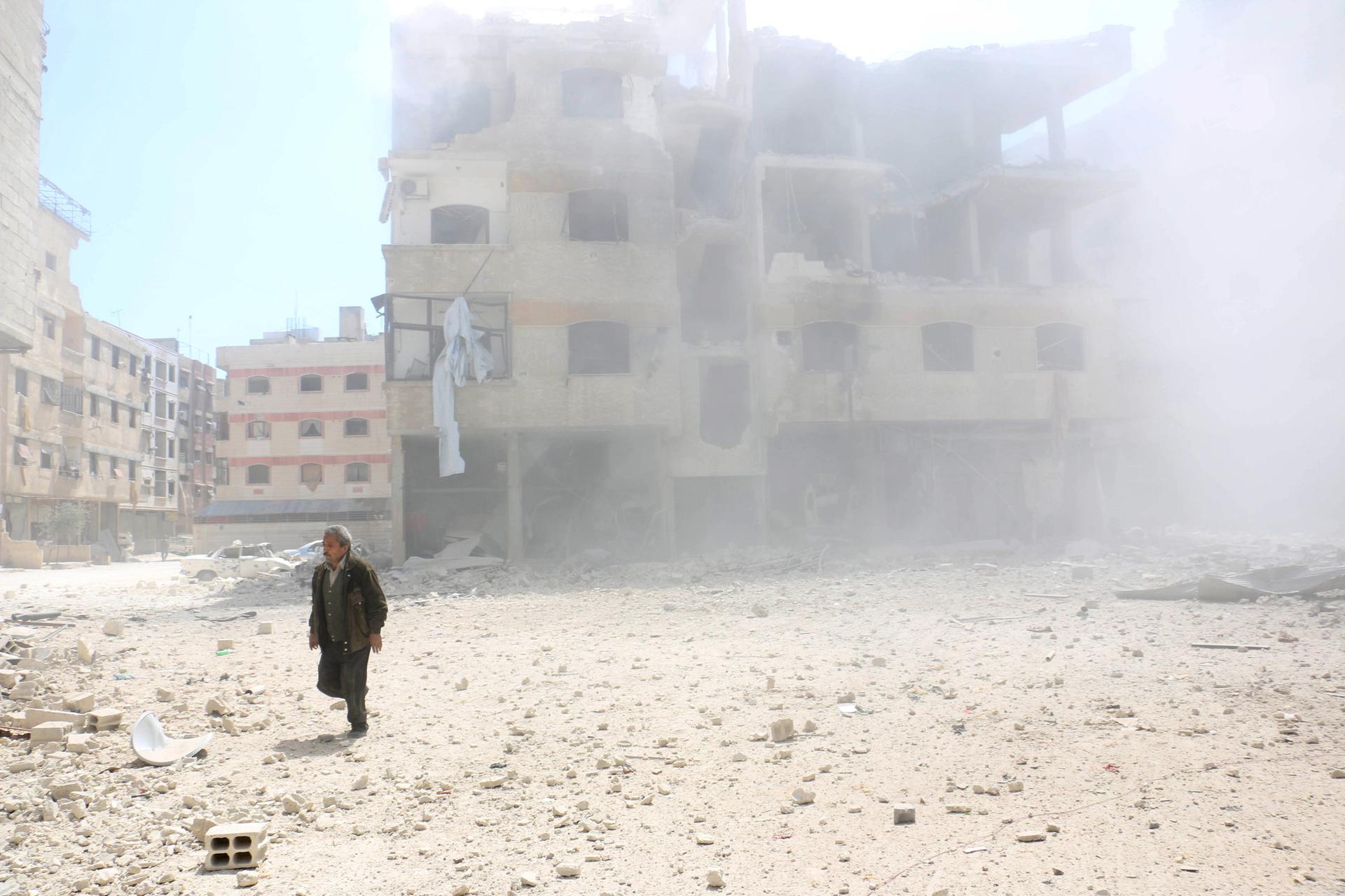 A man walks amid rubble of damaged buildings after what activists said was a mortar shell thrown on an area after air strikes by forces loyal to Syria's President Bashar al-Assad in Ain Tarma, in Eastern Ghouta, a suburb of Damascus, on April 5, 2015