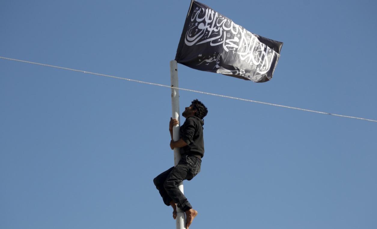 A member of the Nusra Front climbs a pole where the al-Qaeda-affiliate's flag was raised at a central square in the northwestern Syrian city of Ariha, in Idlib province, after a coalition of insurgent groups seized the area on May 29, 2015.