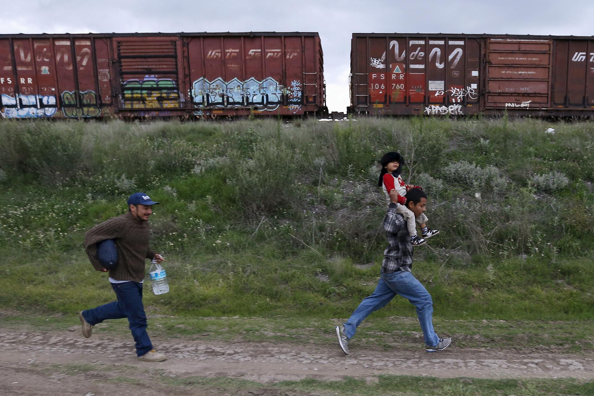 A Salvadoran father carries his son tries as he tries to board a train with another immigrant and head to the Mexican-U.S. border, in Huehuetoca, near Mexico City.