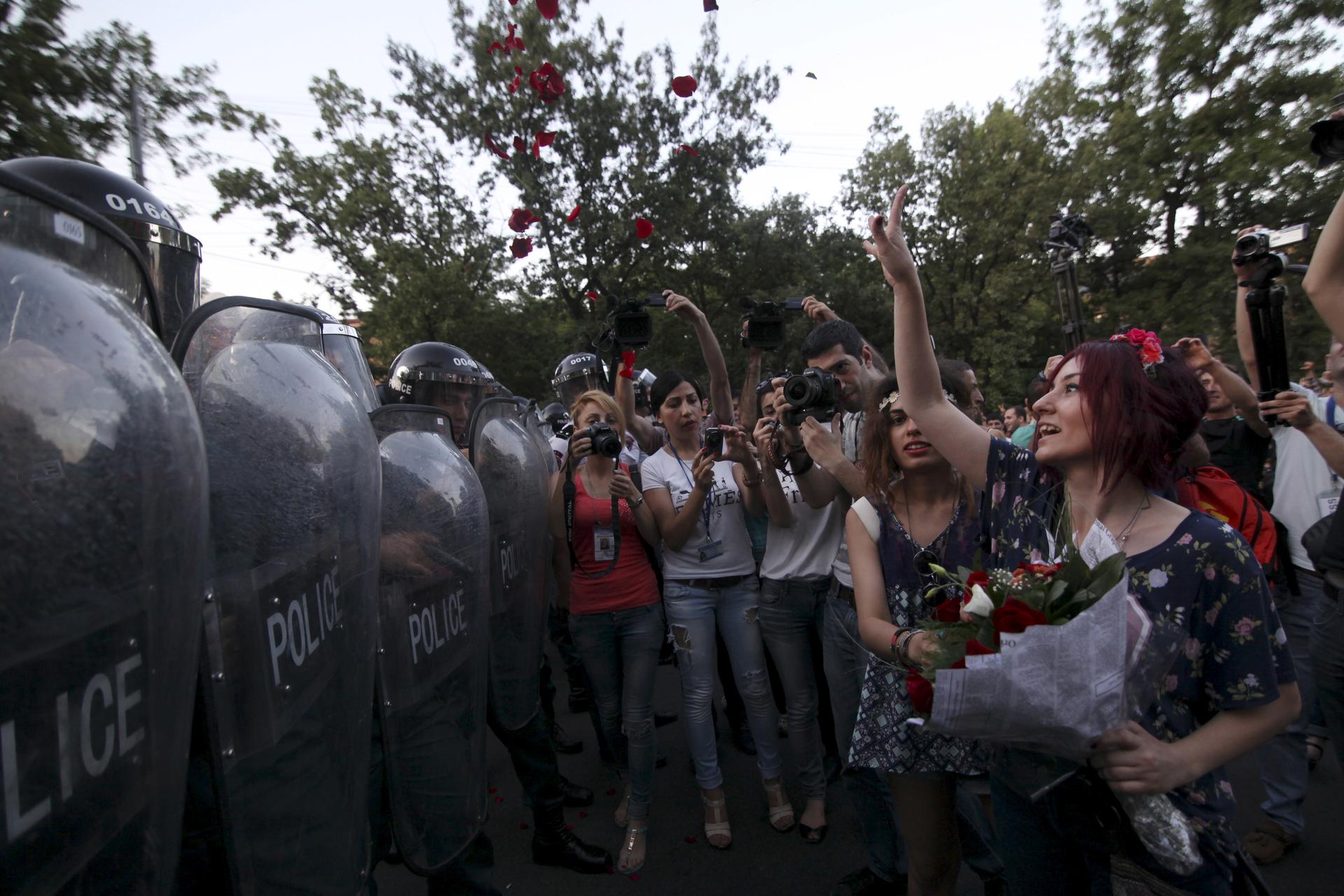 A protester throws rose petals in front of a line of riot police during an #ElectricYerevan protest in Armenia