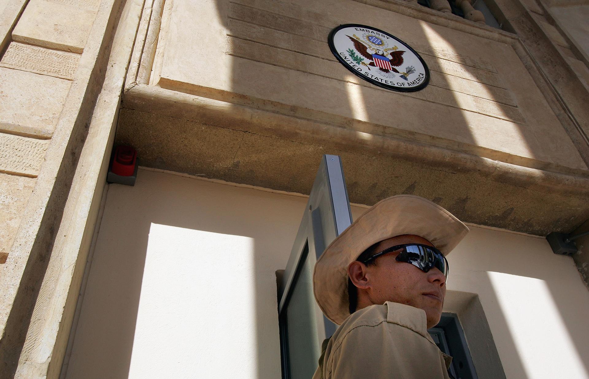 A private security guard stands at the front entrance of the American Embassy building in Iraq inside the green zone in Baghdad in 2004.