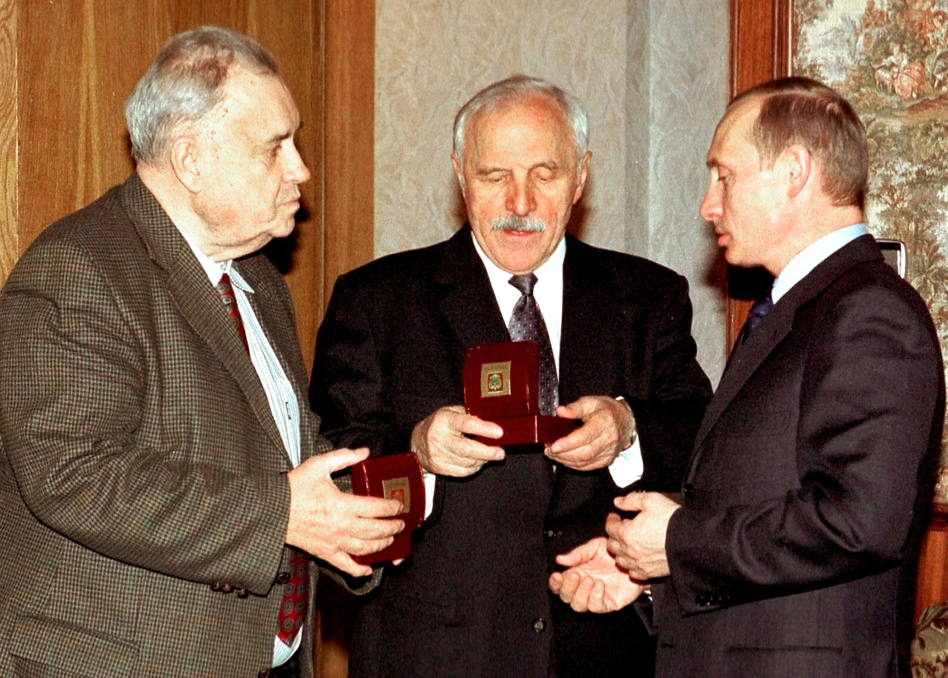 Russian President Vladimir Putin giving 75th birthday presents to actor Mikhail Ulyanov (C) and movie director Eldar Ryazanov (L) back in 2002