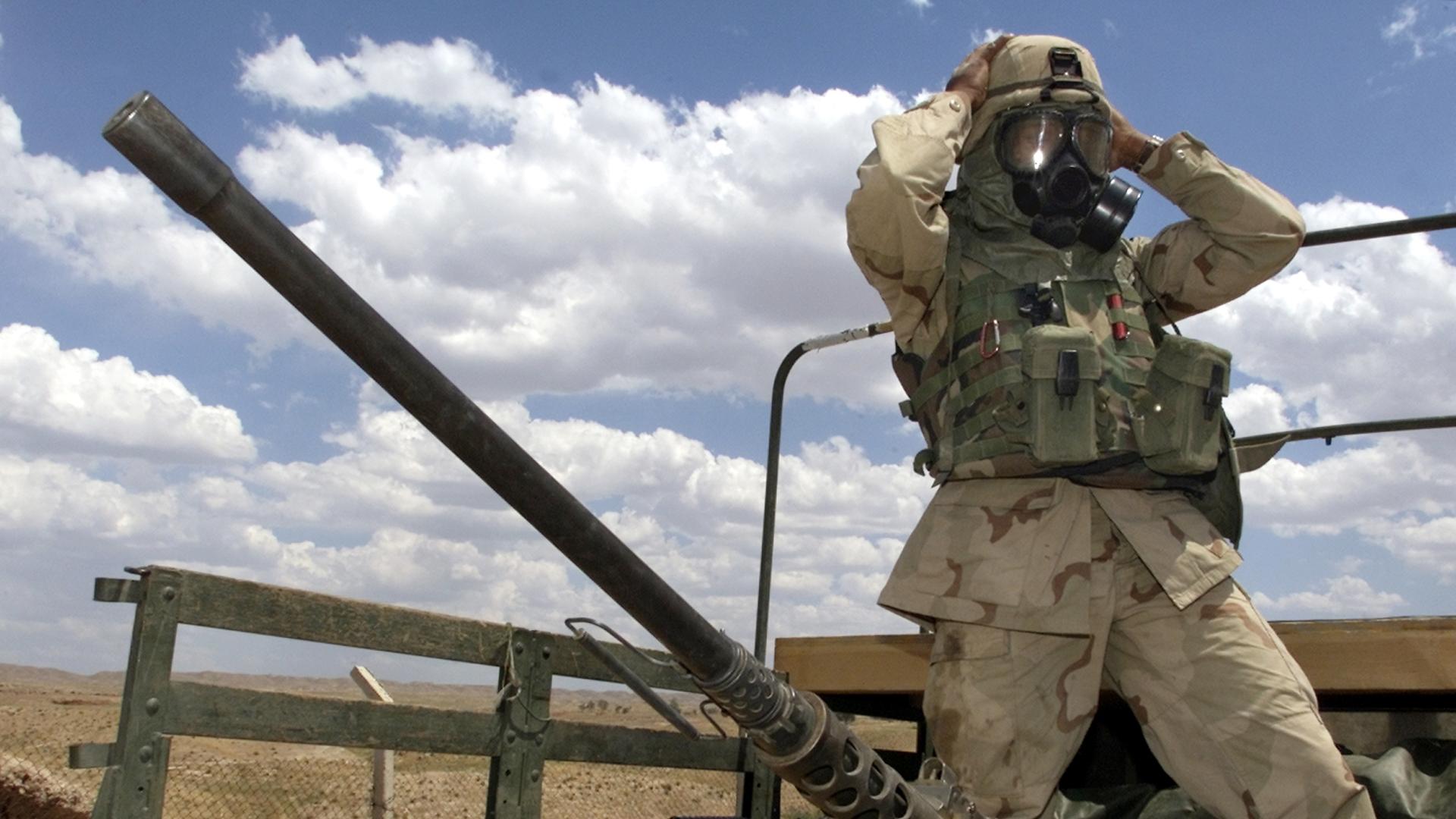 A soldier from the US Army's 173rd Airborne Brigade adjusts his gas mask prior to an air analysis mission near an oil and gas separation plant at the Baba Gurgur oil field outside northern Iraq's town of Kirkuk on May 3, 2003. 