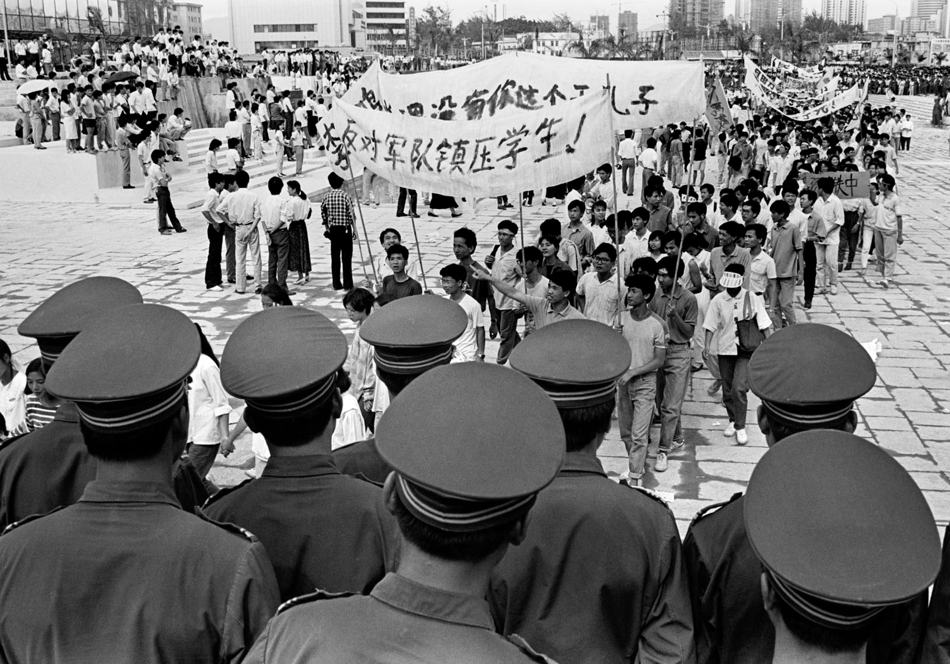 Chinese police monitor a march by tens of thousands of protesters in the special economic zone of Shenzhen in southern China on May 22, 1989. Hundreds of people were killed in Beijing on June 4, 1989 when Chinese troops crushed demonstrations which called
