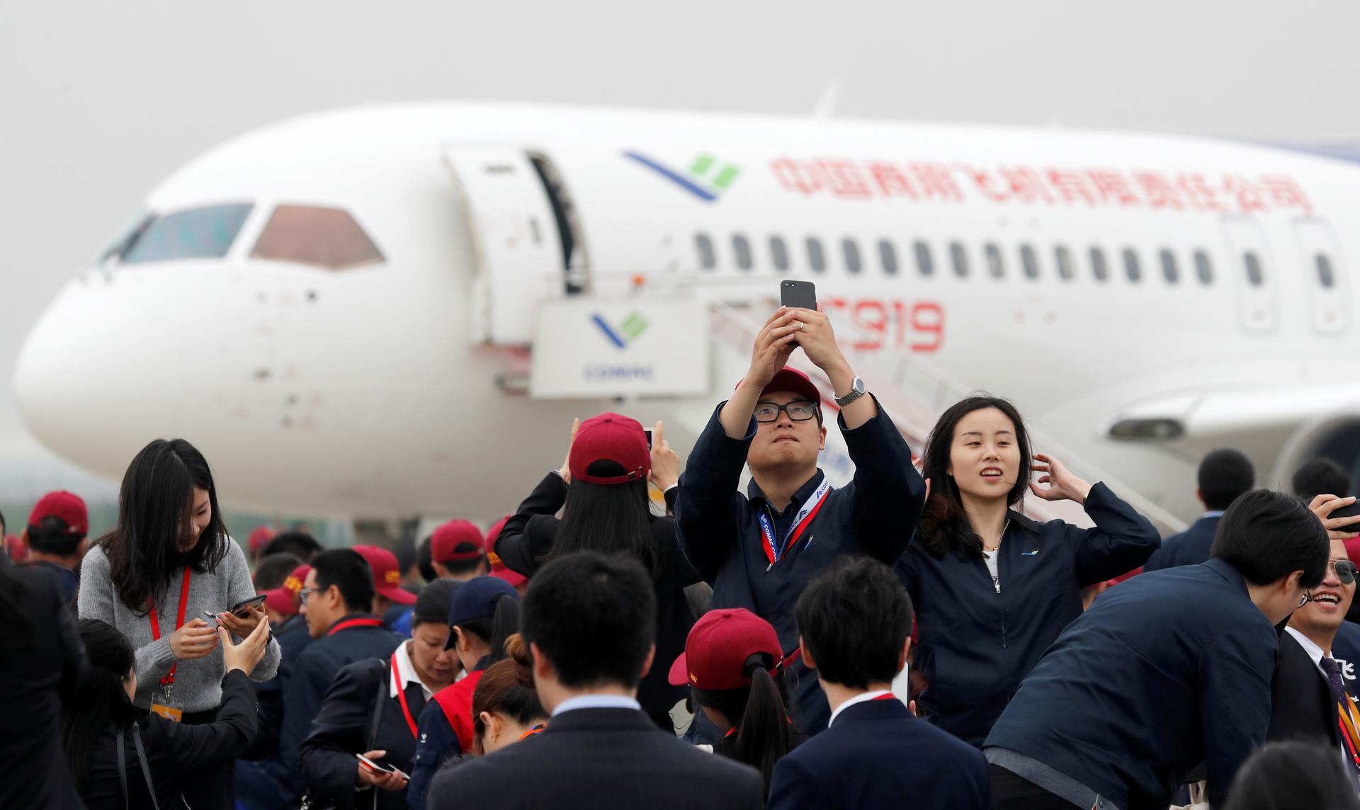 Attendees take photos in front of a Chinese C919 passenger jet after its first flight at Pudong International Airport in Shanghai.