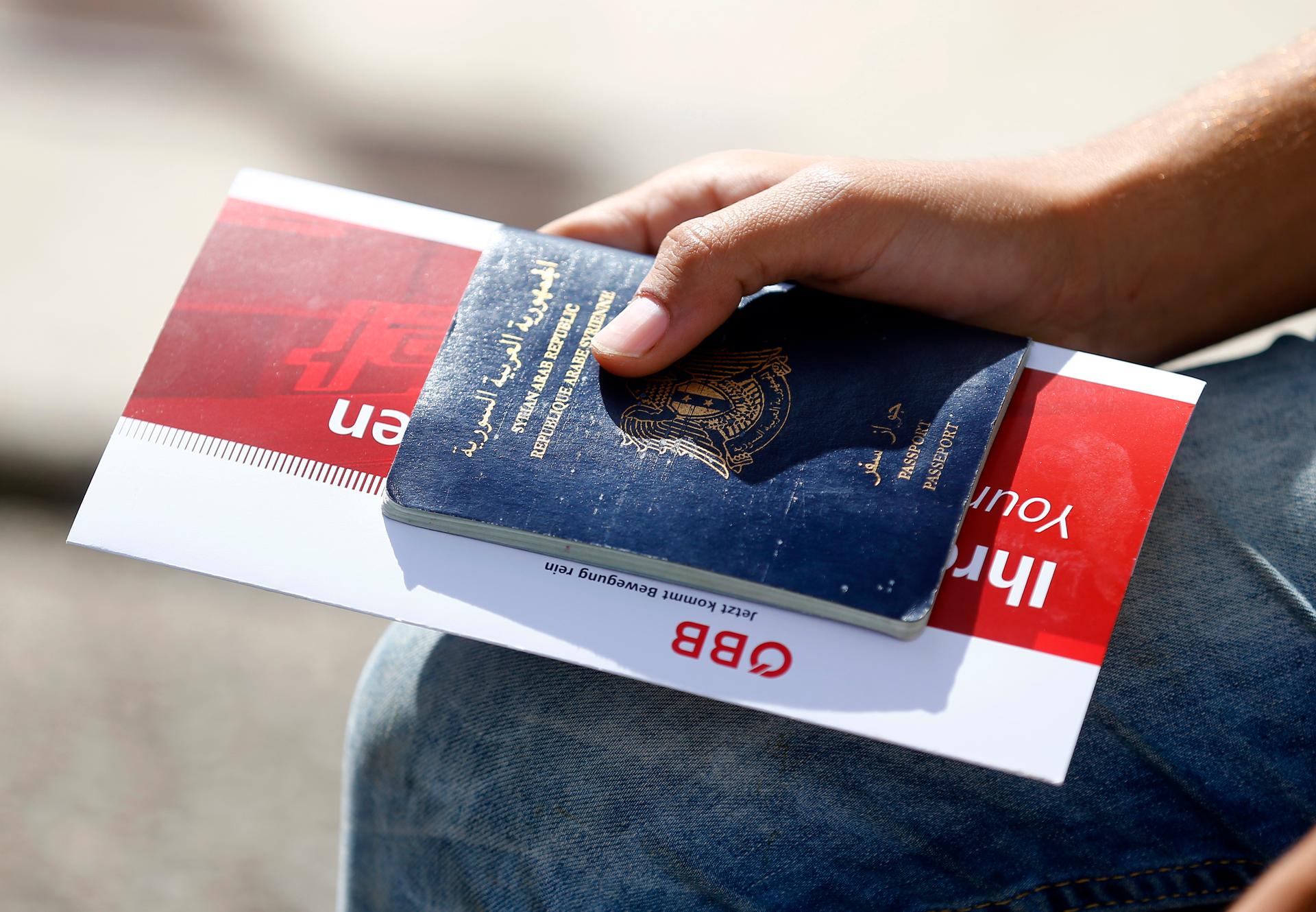 A migrant holds his passport and a train ticket in Freilassing, Germany September 15, 2015.