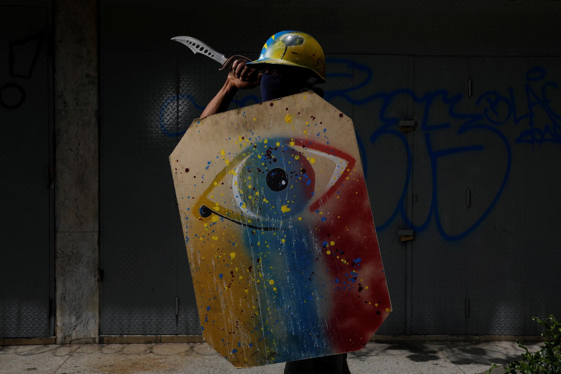 A demonstrator holds a painted shield and a knife.