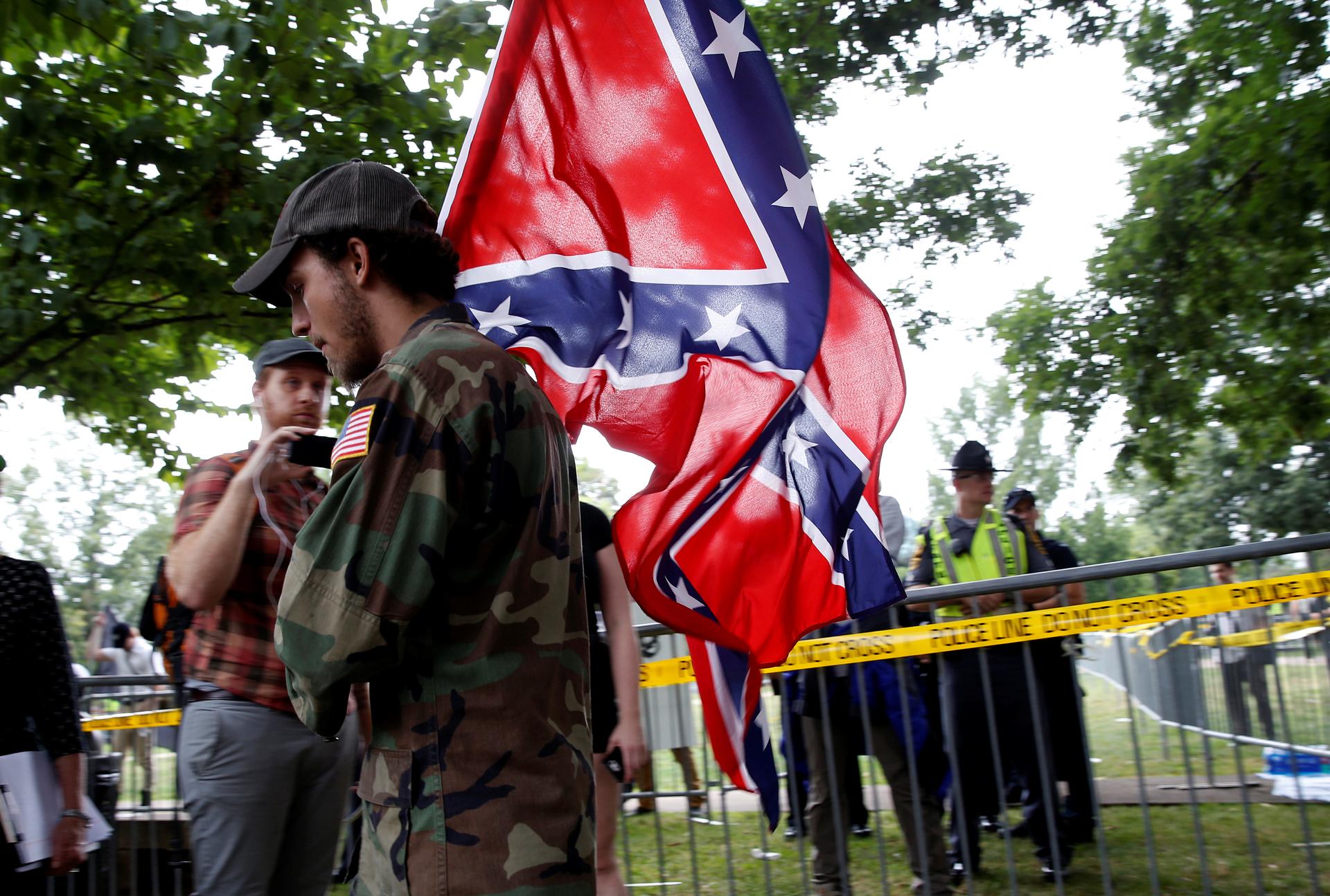 A white nationalist carries the Confederate flag as he arrives for a rally in Charlottesville, Virginia, US, August 12, 2017.