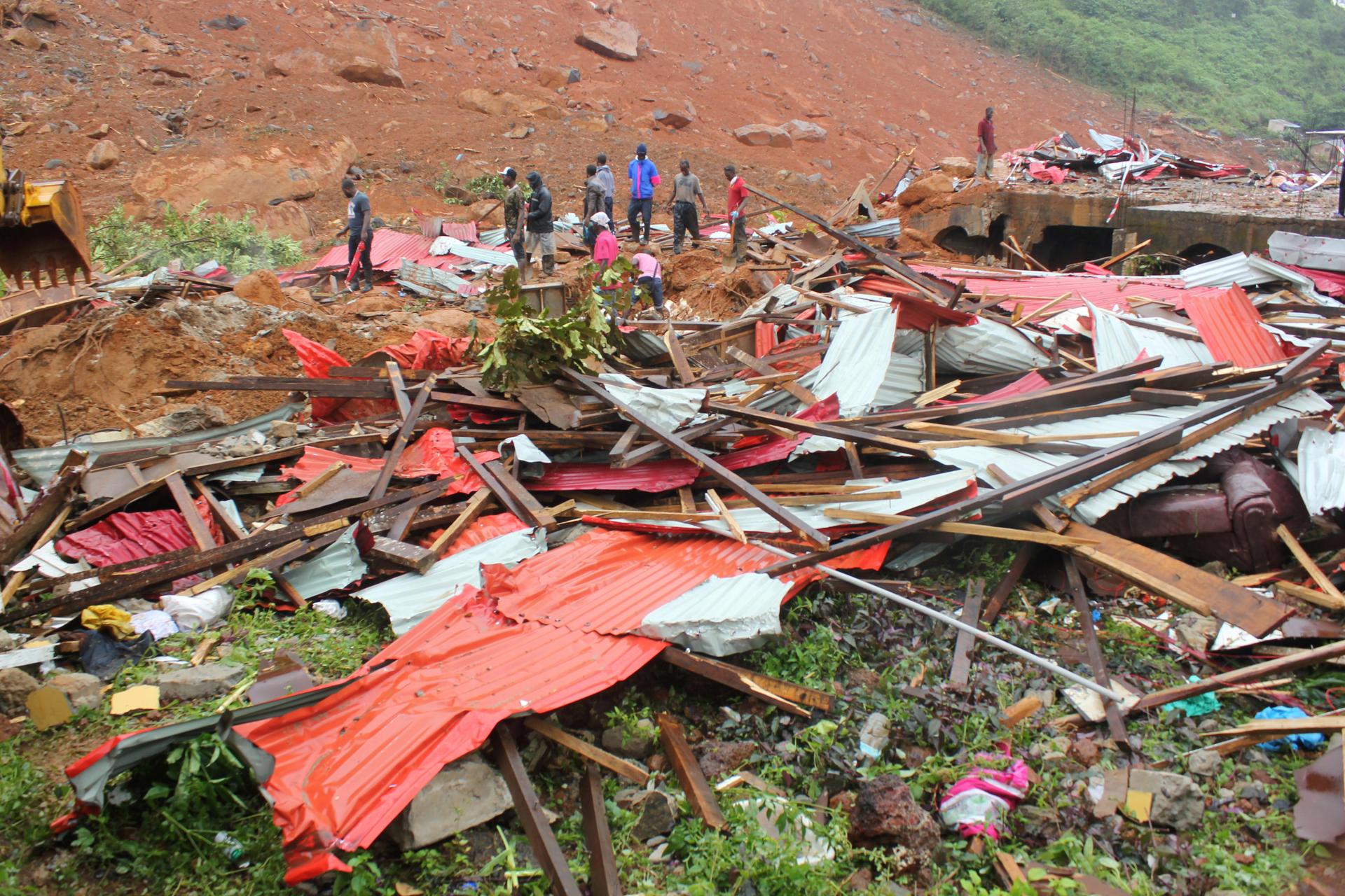 People inspect the damage after a mudslide in the mountain town of Regent, Sierra Leone. 