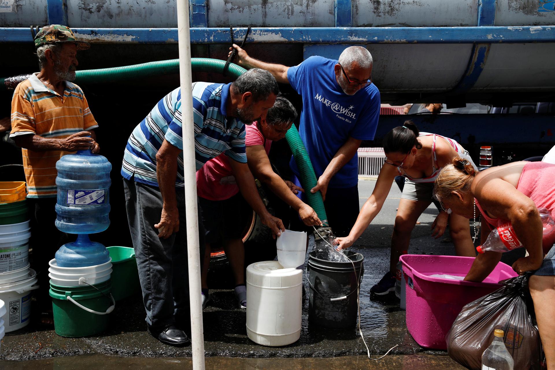 People queue to fill containers with water from a tank truck at an area hit by Hurricane Maria in Canovanas, Puerto Rico.