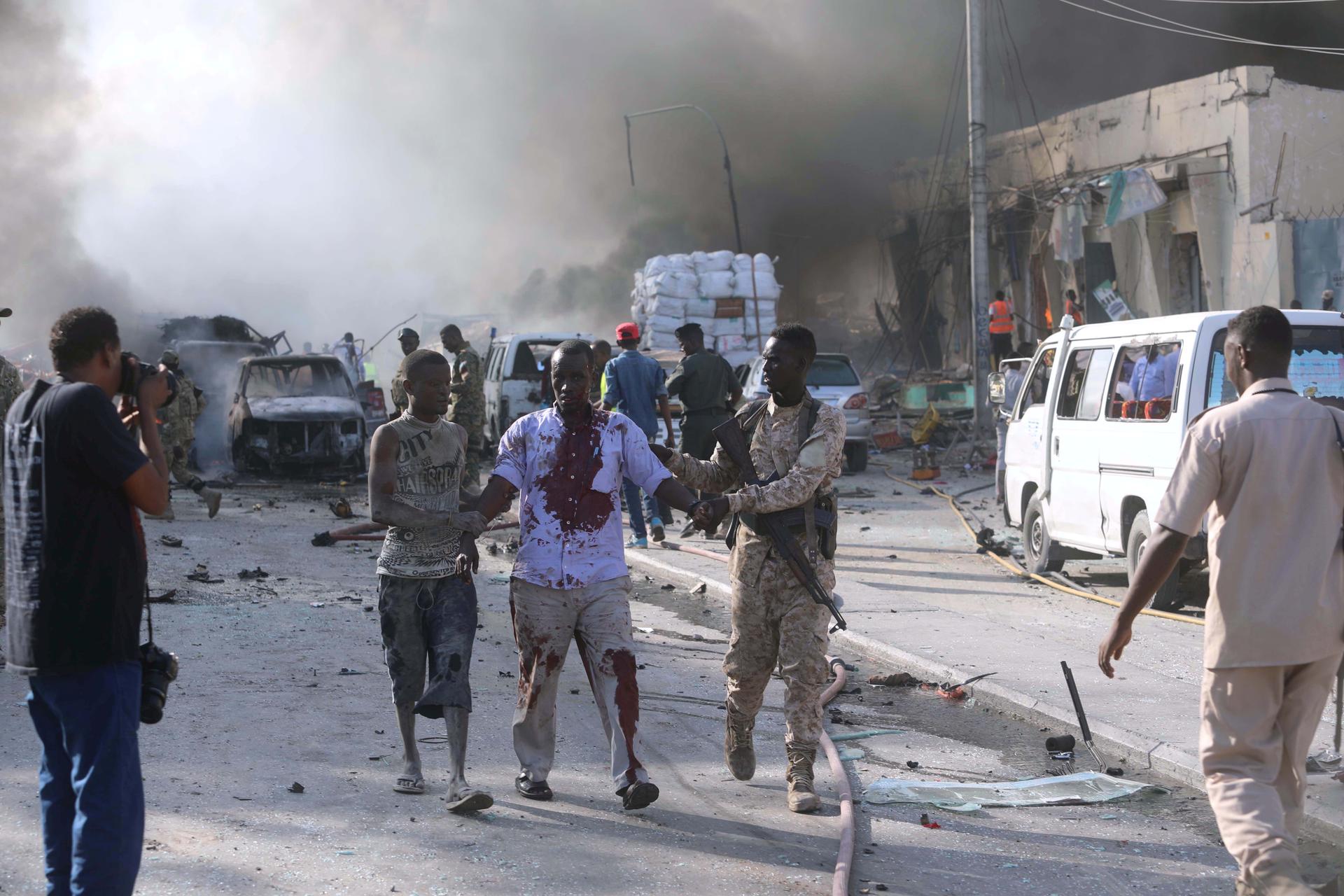 A Somali government soldier evacuates an injured man from the scene of an explosion.