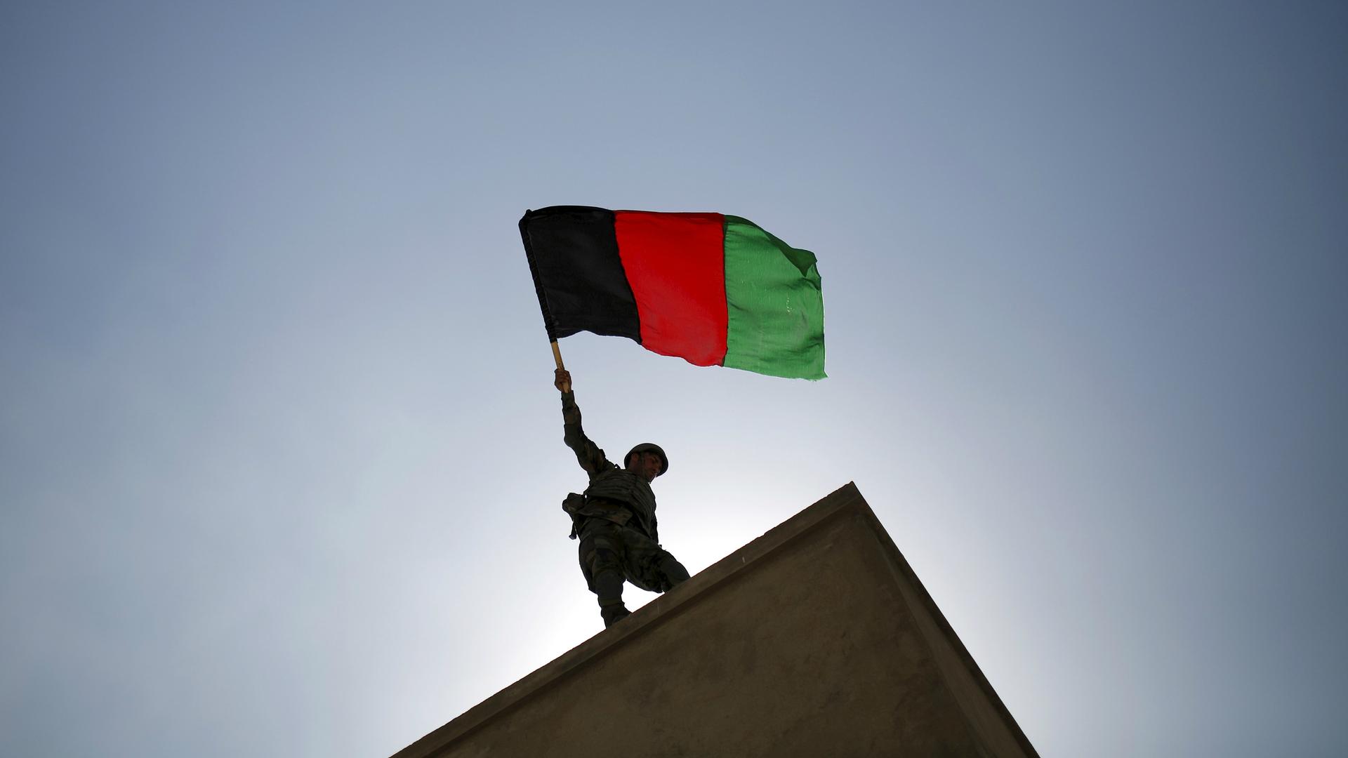 An Afghan National Army officer holds an Afghanistan flag during a training exercise at the Kabul Military Training Centre in Afghanistan, Oct. 7, 2015.