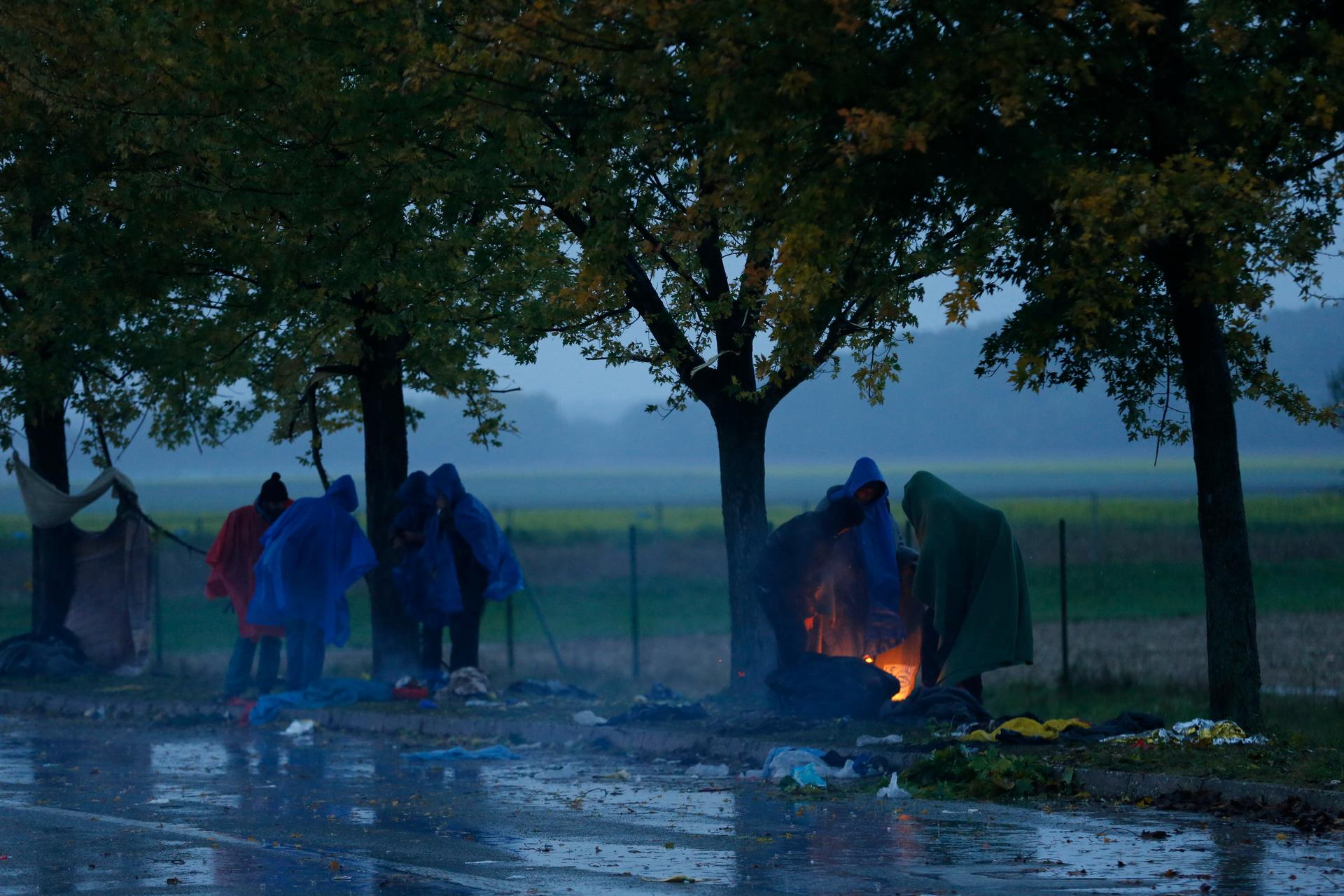 Migrants warm themselves next to a fire as they wait to cross the border from Croatia into Slovenia.